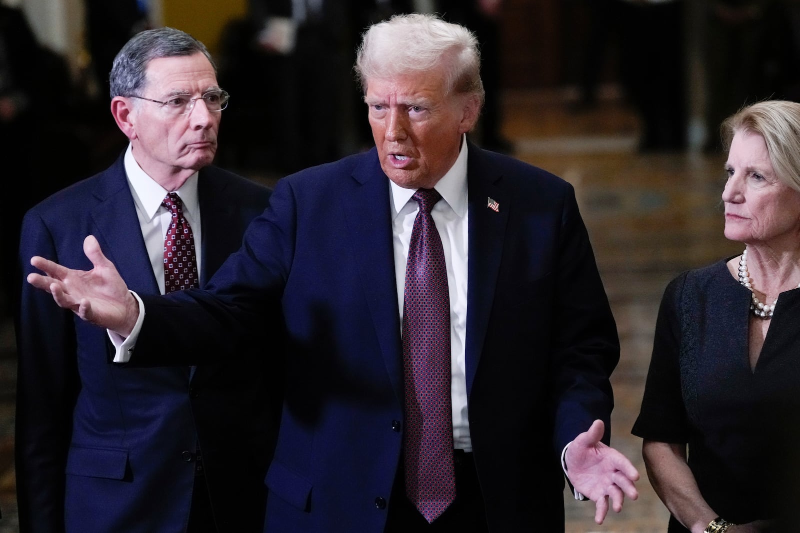 FILE - President-elect Donald Trump talks to reporters after a meeting with Republican leadership at the Capitol, Jan. 8, 2025, in Washington. At left is Sen. John Barrasso, R-Wyo., and at right is Sen. Shelley Moore Capito, R-W.Va. (AP Photo/Steve Helber, File)