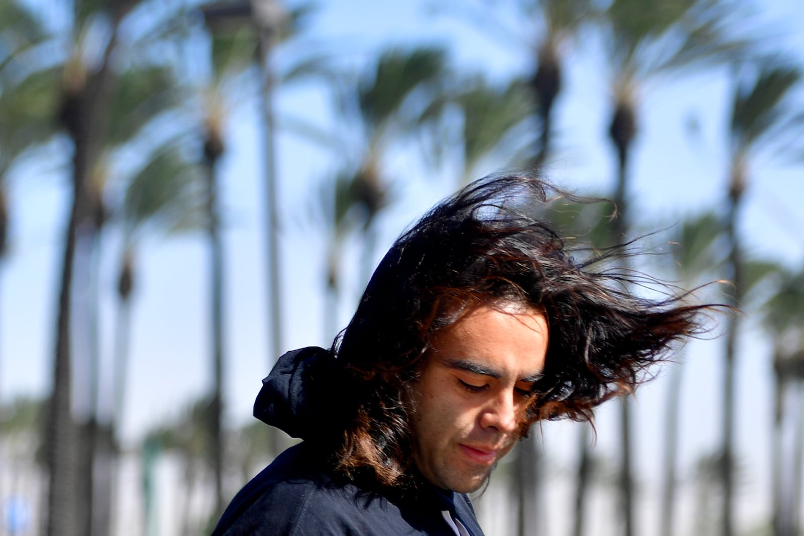 FILE - Los Angeles resident Moses Gonzalez's hair flies as he fills up gas at Ontario's Speedway during high winds Monday, Oct. 26, 2020. (Cindy Yamanaka/The Orange County Register via AP, File)