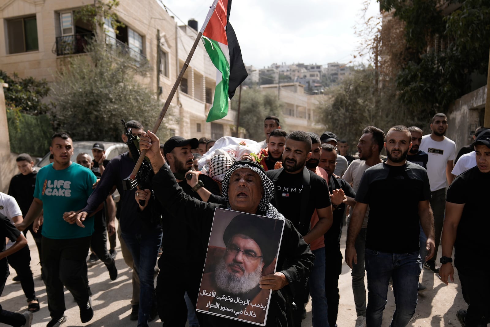 Palestinian activist Khairi Hanoun holds up a poster of Hassan Nasrallah, the leader of Hezbollah who was killed by an Israeli strike in September, while mourning Rayan al-Sayed, a Palestinian killed in an Israeli raid Monday in the West Bank city of Jenin, during Al-Sayed's funeral, Tuesday, Oct. 15, 2024. (AP Photo/Majdi Mohammed)