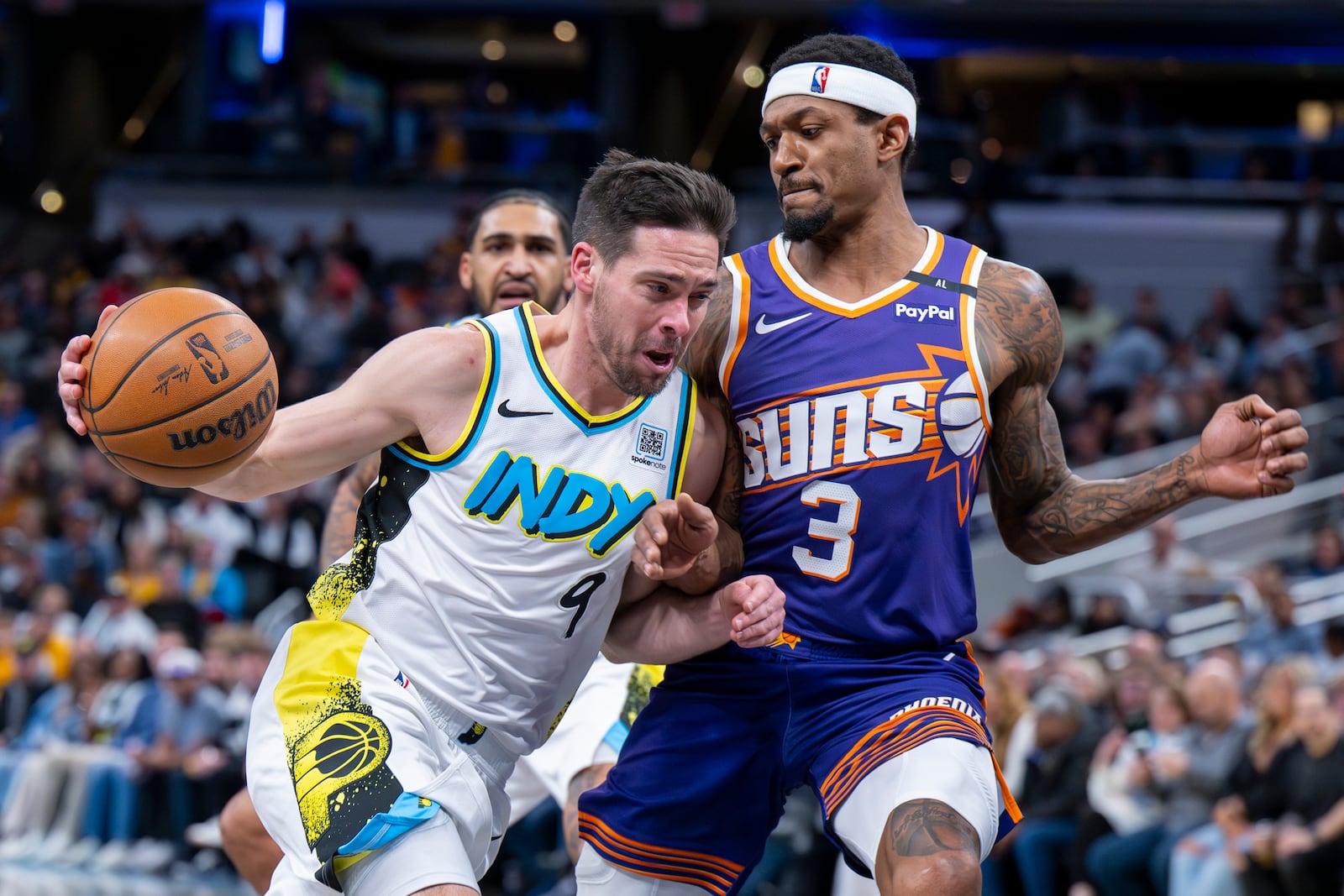 Indiana Pacers guard T.J. McConnell (9) drives the ball into the defense of Phoenix Suns guard Bradley Beal (3) during the second half of an NBA basketball game in Indianapolis, Saturday, Jan. 4, 2025. (AP Photo/Doug McSchooler)