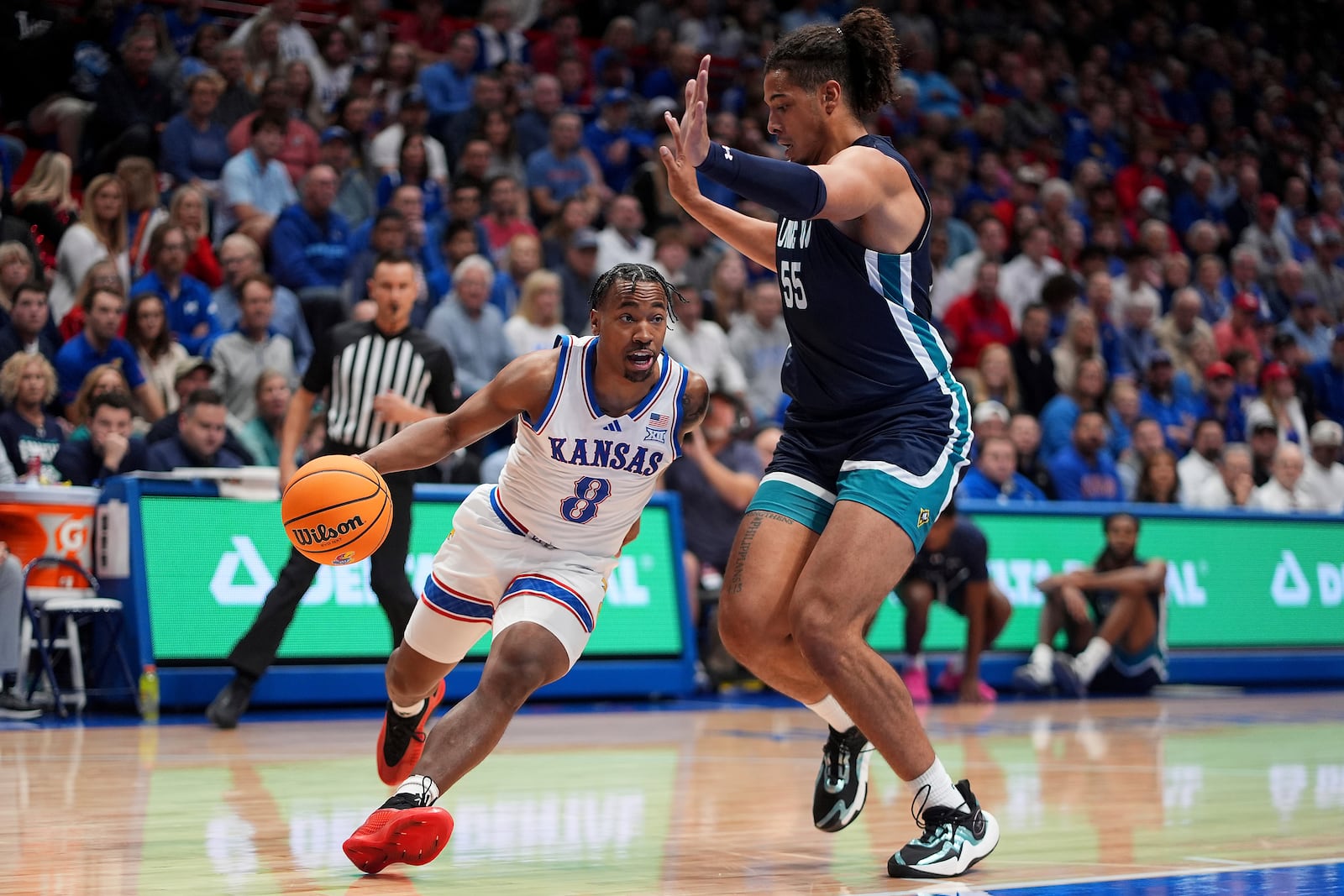 Kansas guard David Coit (8) drives past UNC Wilmington forward Harlan Obioha (55) during the first half of an NCAA college basketball game Tuesday, Nov. 19, 2024, in Lawrence, Kan. (AP Photo/Charlie Riedel)