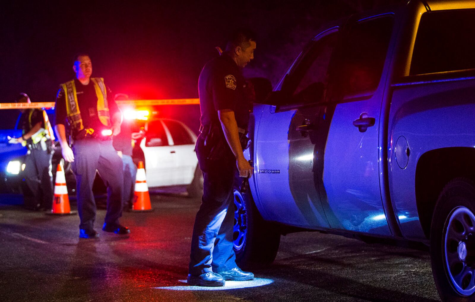 An Austin police officer directs a vehicle away from the scene of an explosion in Austin, Texas, Sunday, March 18, 2018. At least a few people were injured in another explosion in Texas' capital late Sunday, after three package bombs detonated this month in other parts of the city, killing two people and injuring two others. (Nick Wagner/Austin American-Statesman via AP)