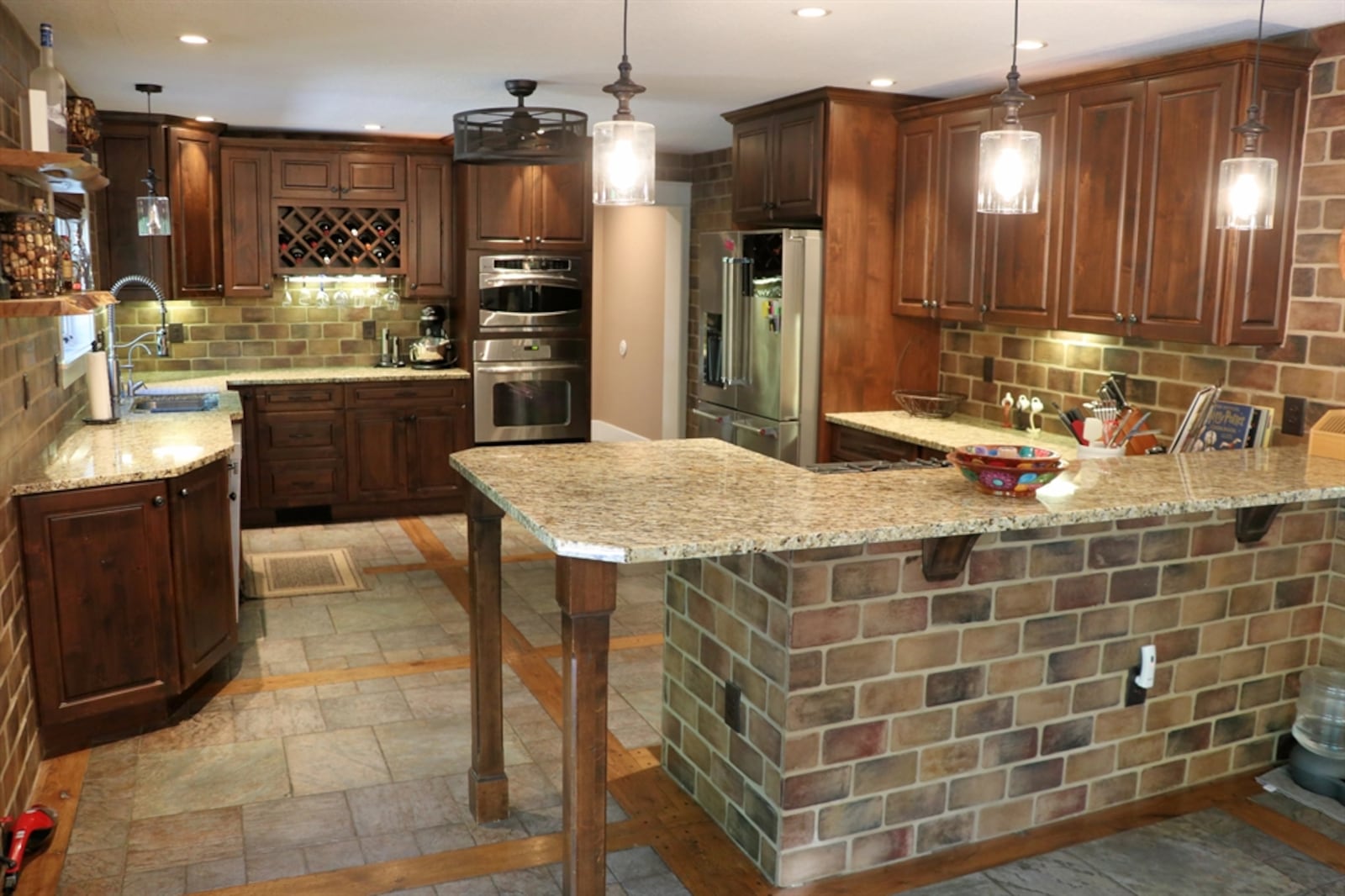 In the kitchen, a peninsula features an extended granite counter with wooden table legs to create a table setting. 