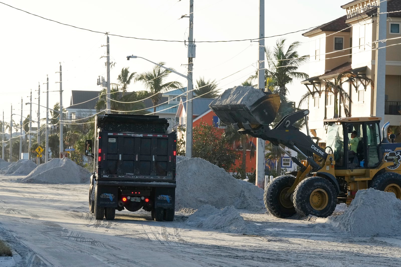 Public work employees remove sand that was pushed to the streets by wind and storm surge from Hurricane Milton, Friday, Oct. 11, 2024, in Fort Myers Beach, Fla. (AP Photo/Marta Lavandier)