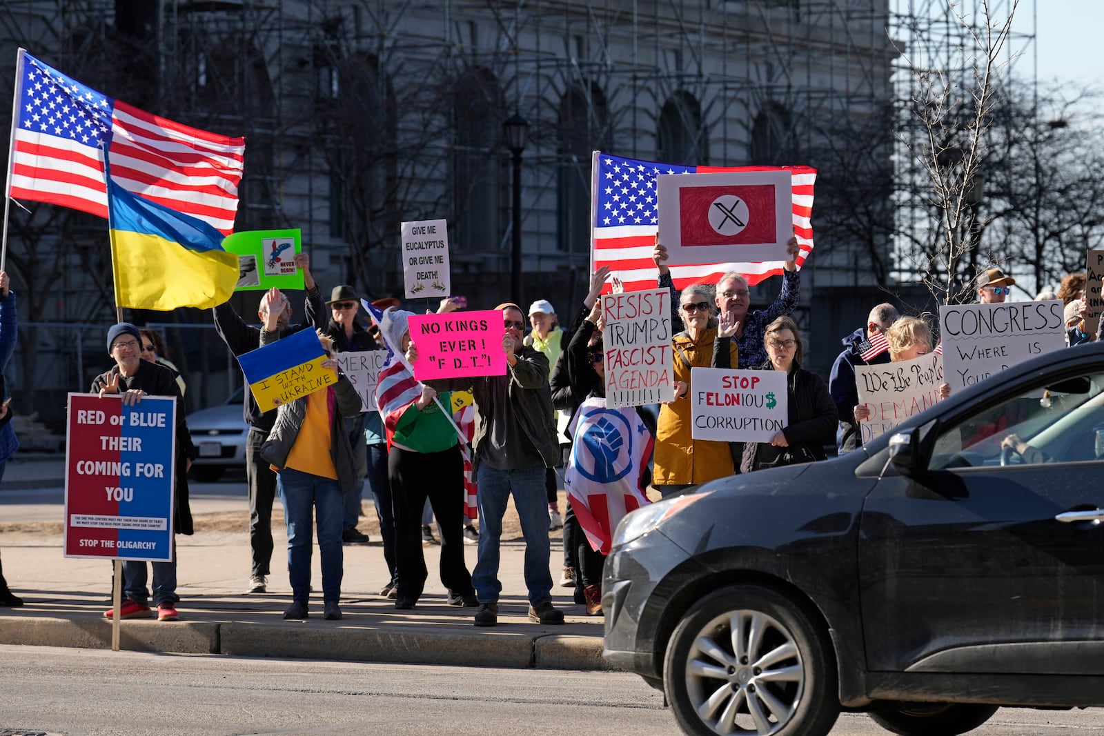 Protestors against the Trump administration hold signs for passing traffic Tuesday, March 4, 2025, in Cleveland. (AP Photo/Sue Ogrocki)