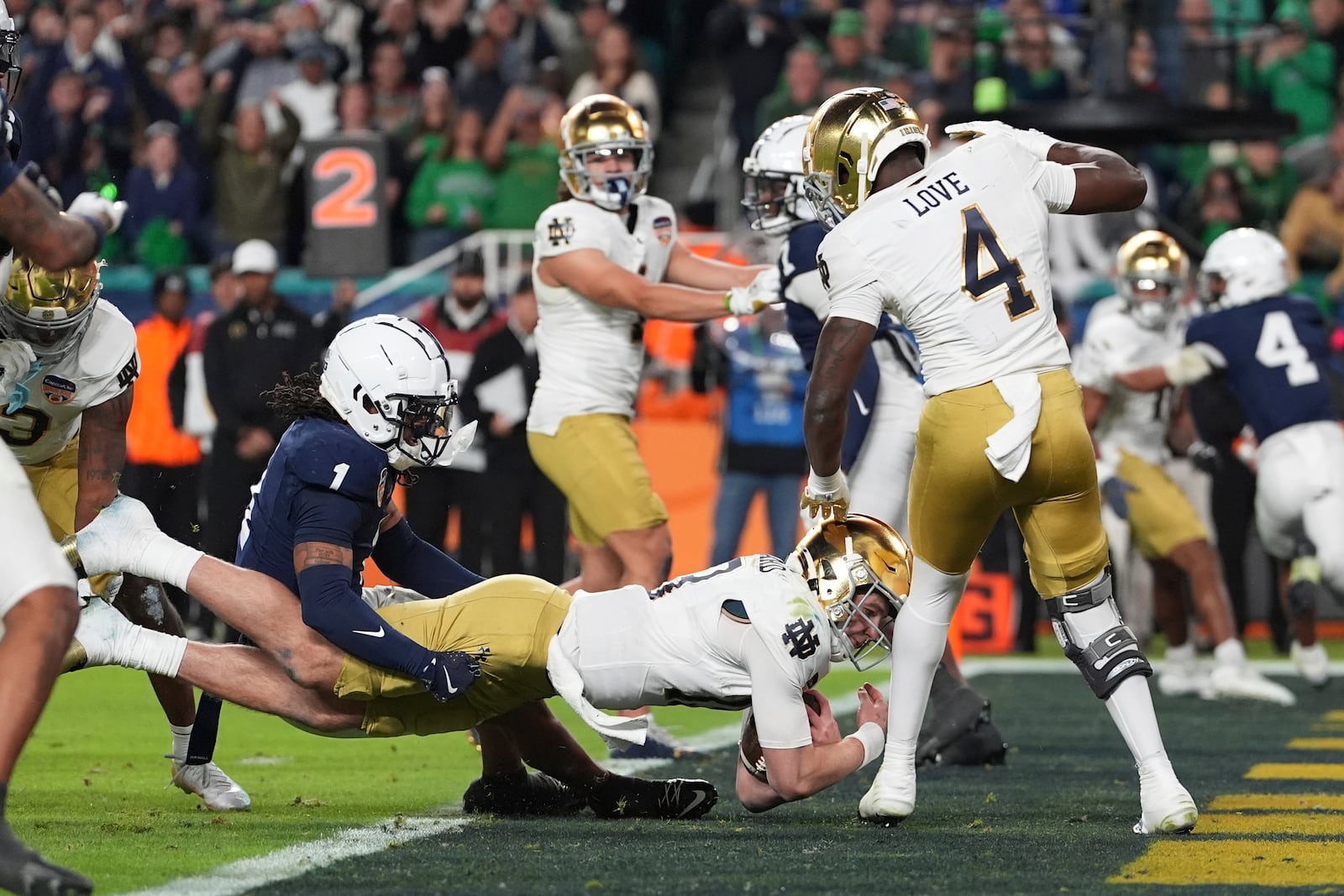 Penn State safety Jaylen Reed (1) attempts to hold Notre Dame quarterback Riley Leonard (13) as he scores a touchdown during the second half of the Orange Bowl NCAA College Football Playoff semifinal game, Thursday, Jan. 9, 2025, in Miami Gardens, Fla. (AP Photo/Rebecca Blackwell)