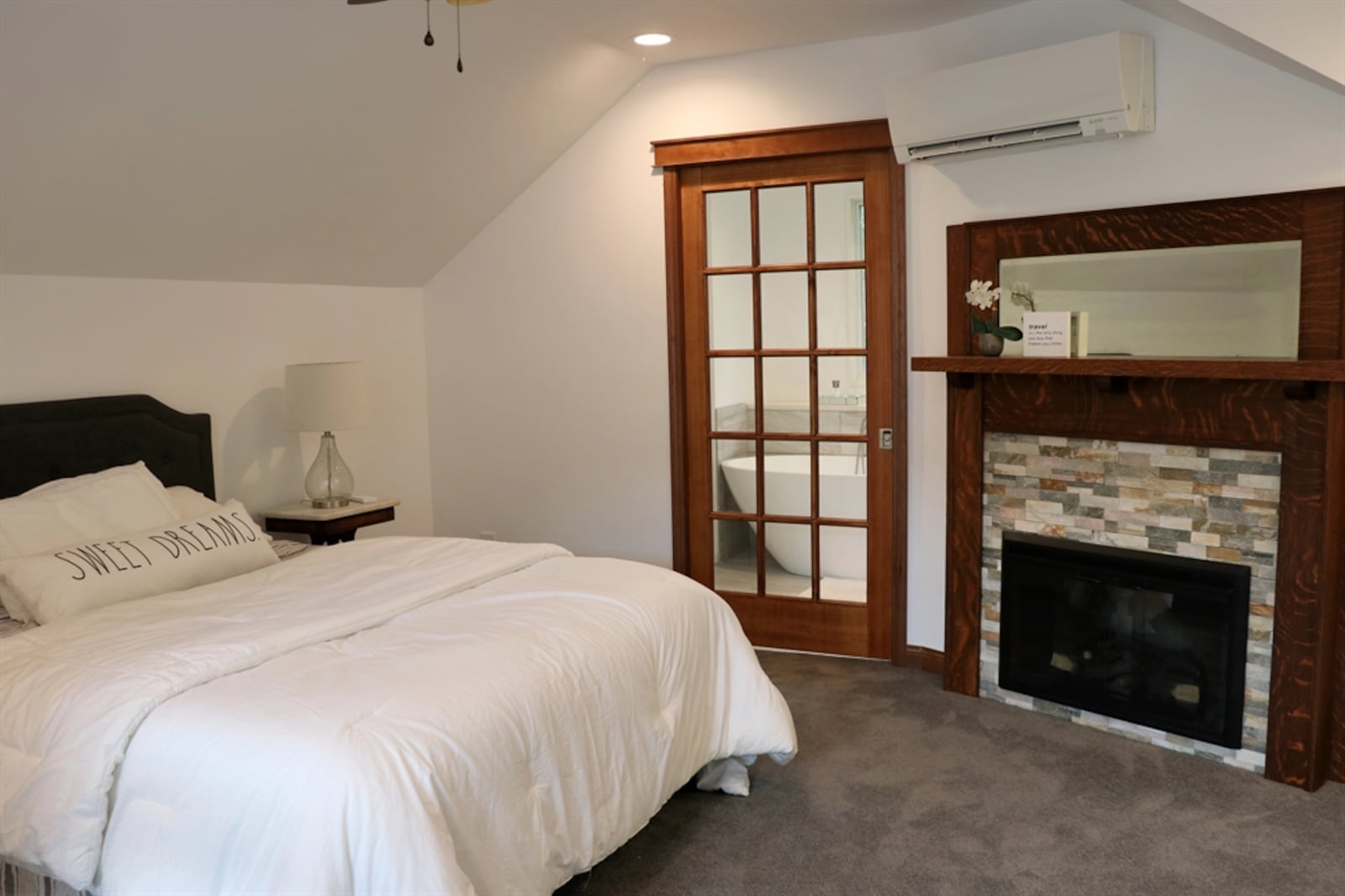 The third-floor bedroom features a gas fireplace with a stack-stone surround and a custom wood mantel with mirror.