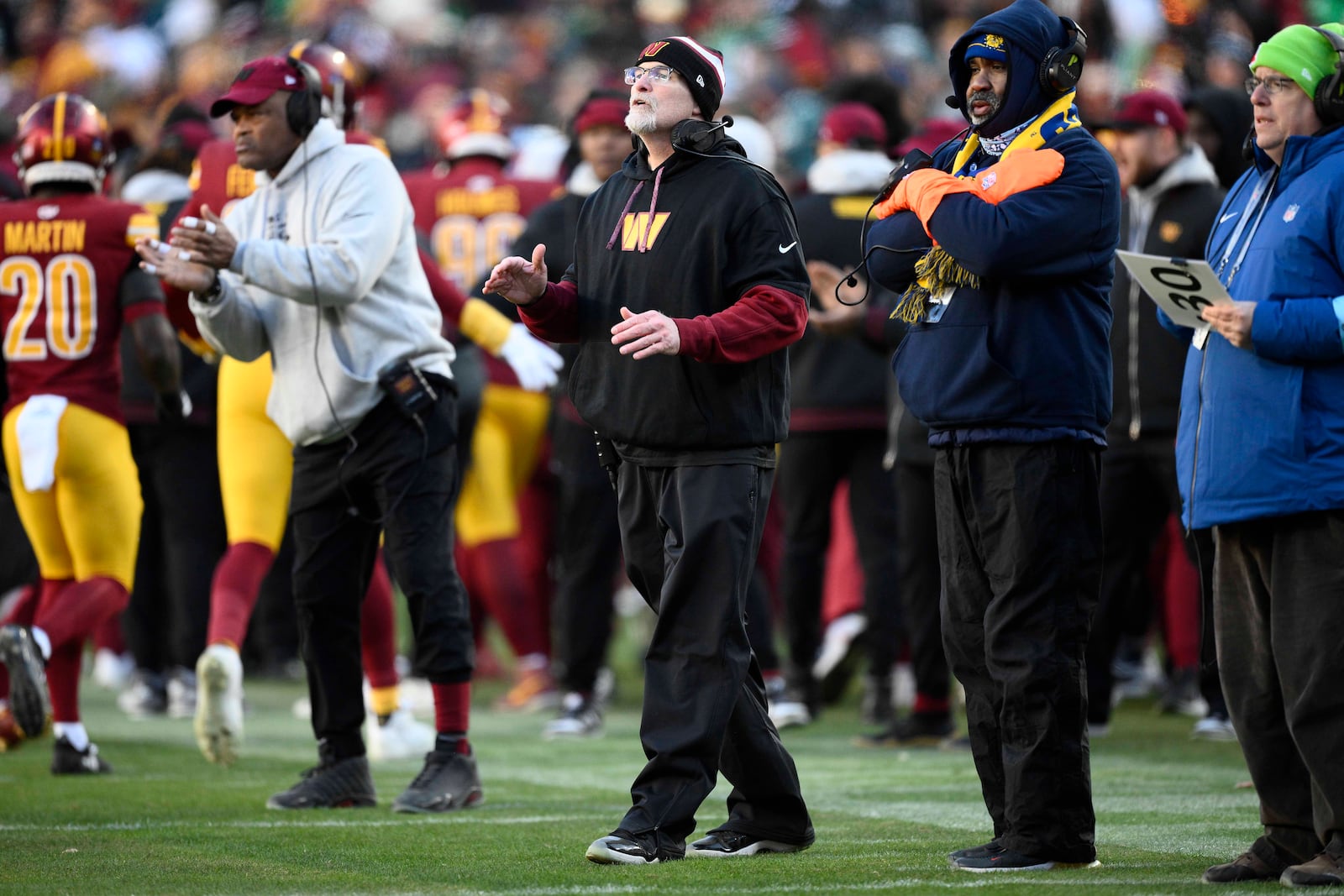 Washington Commanders head coach Dan Quinn, center, on the sidelines during the second half of an NFL football game against the Philadelphia Eagles, Sunday, Dec. 22, 2024, in Landover, Md. (AP Photo/Nick Wass)