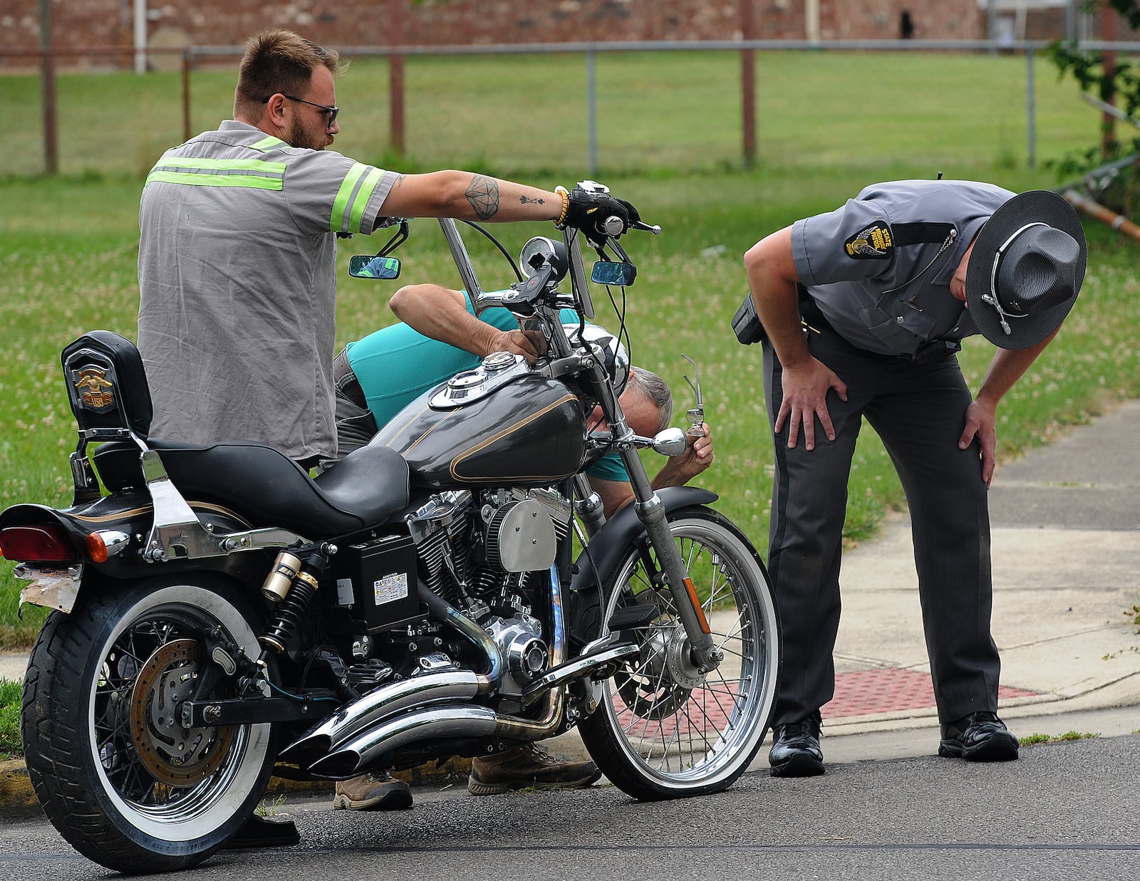 An Ohio State Highway Patrol trooper looks over a motorcycle Thursday, June 13, 2024 ,removed from a home in the 1000 block of Colorado Drive in Xenia. The Bureau of Alcohol, Tobacco and Firearms and Xenia police were also at the scene for the investigation. MARSHALL GORBY\STAFF 