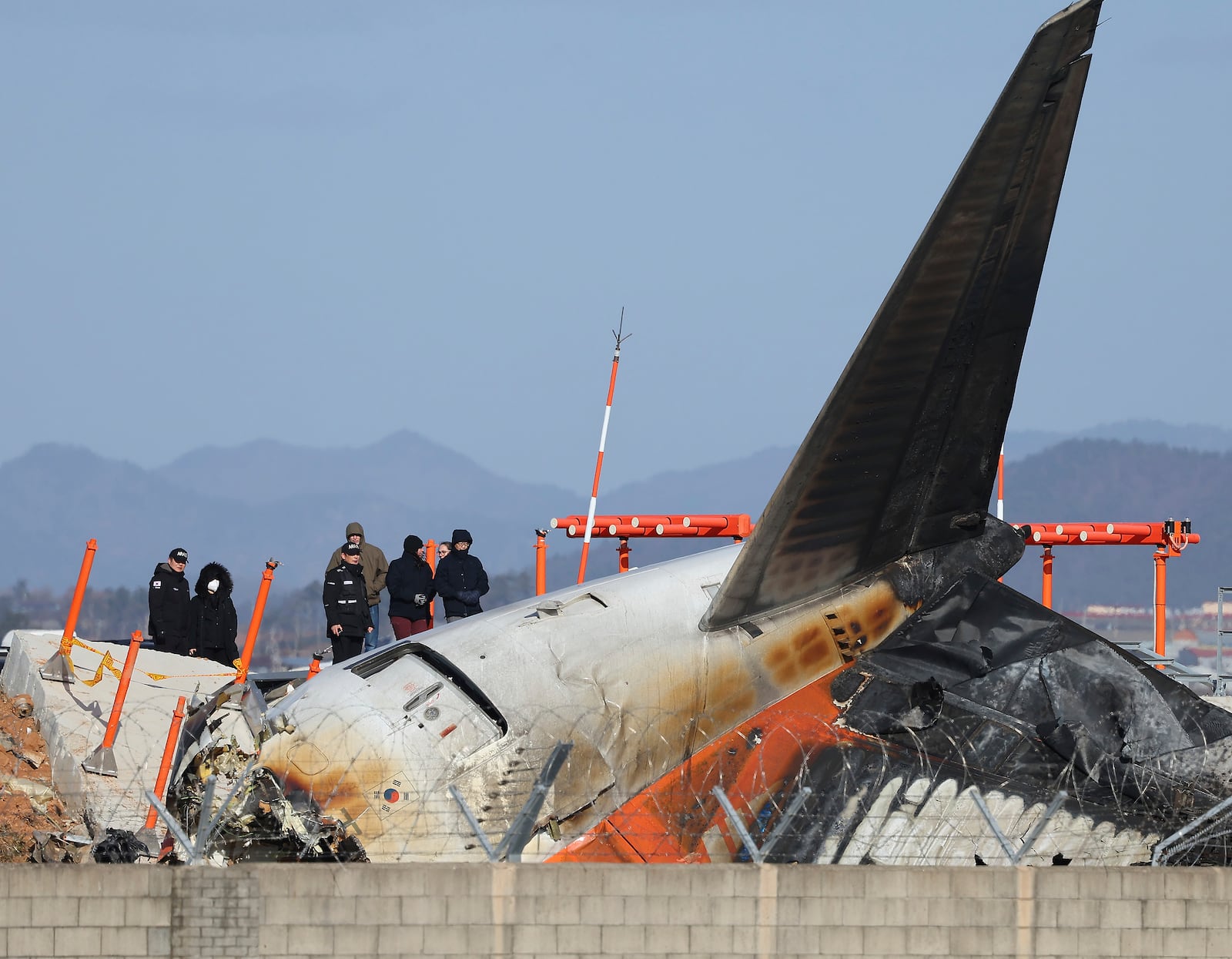 Experts from the U.S. National Transportation Safety Board (NTSB) and joint investigation team between the U.S. and South Korea check the site of a plane crash at Muan International Airport in Muan, South Korea, Tuesday, Dec. 31, 2024. (Son Hyung-joo/Yonhap via AP)