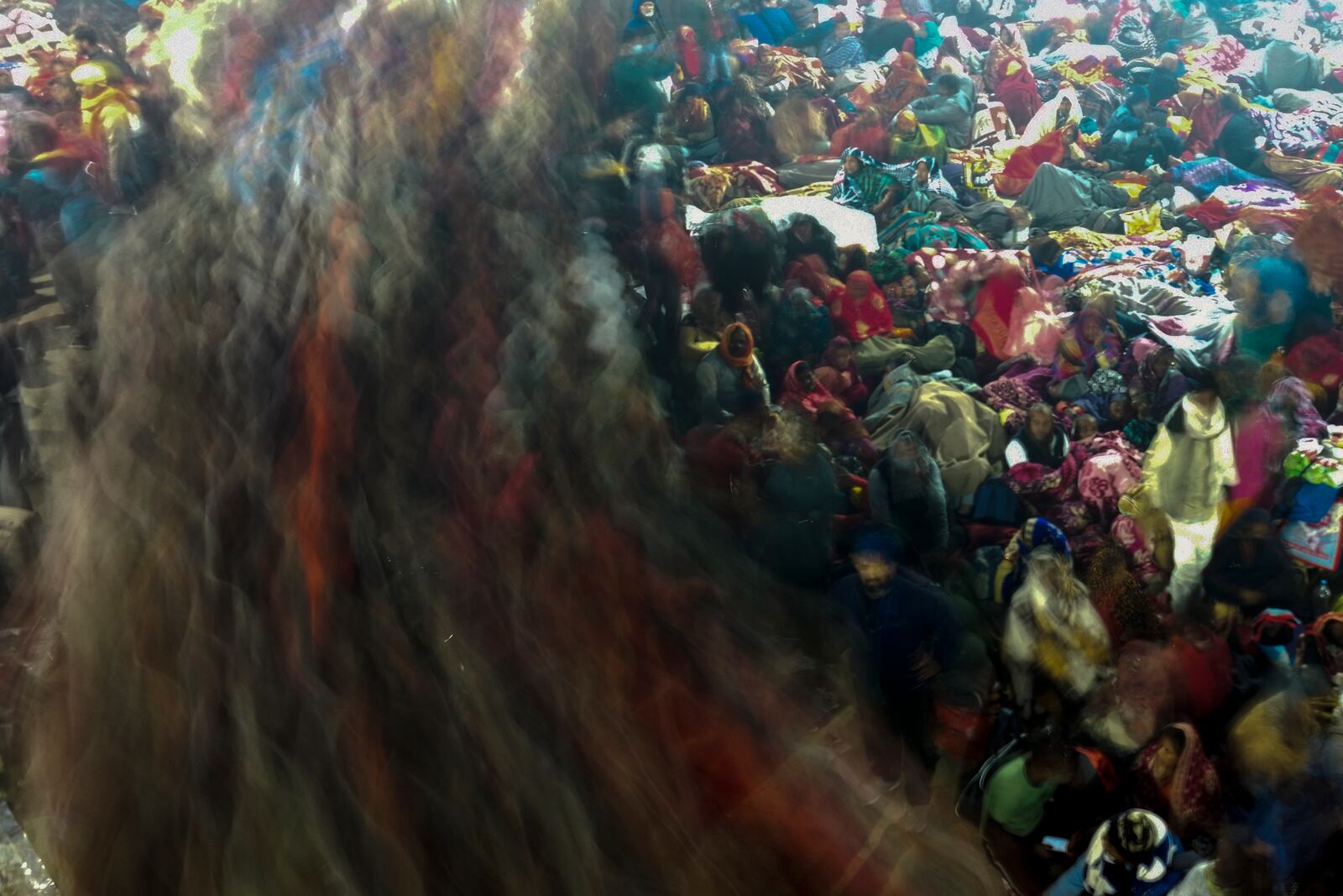 Hindu devotees rest by the banks of the Sangam, the confluence of the Ganges, the Yamuna and the mythical Saraswati rivers, as others move past them in the early hours of 'Mauni Amavasya' or new moon day during the Maha Kumbh festival, in Prayagraj, Uttar Pradesh, India, Wednesday, Jan. 29, 2025. (AP Photo/Rajesh Kumar Singh)