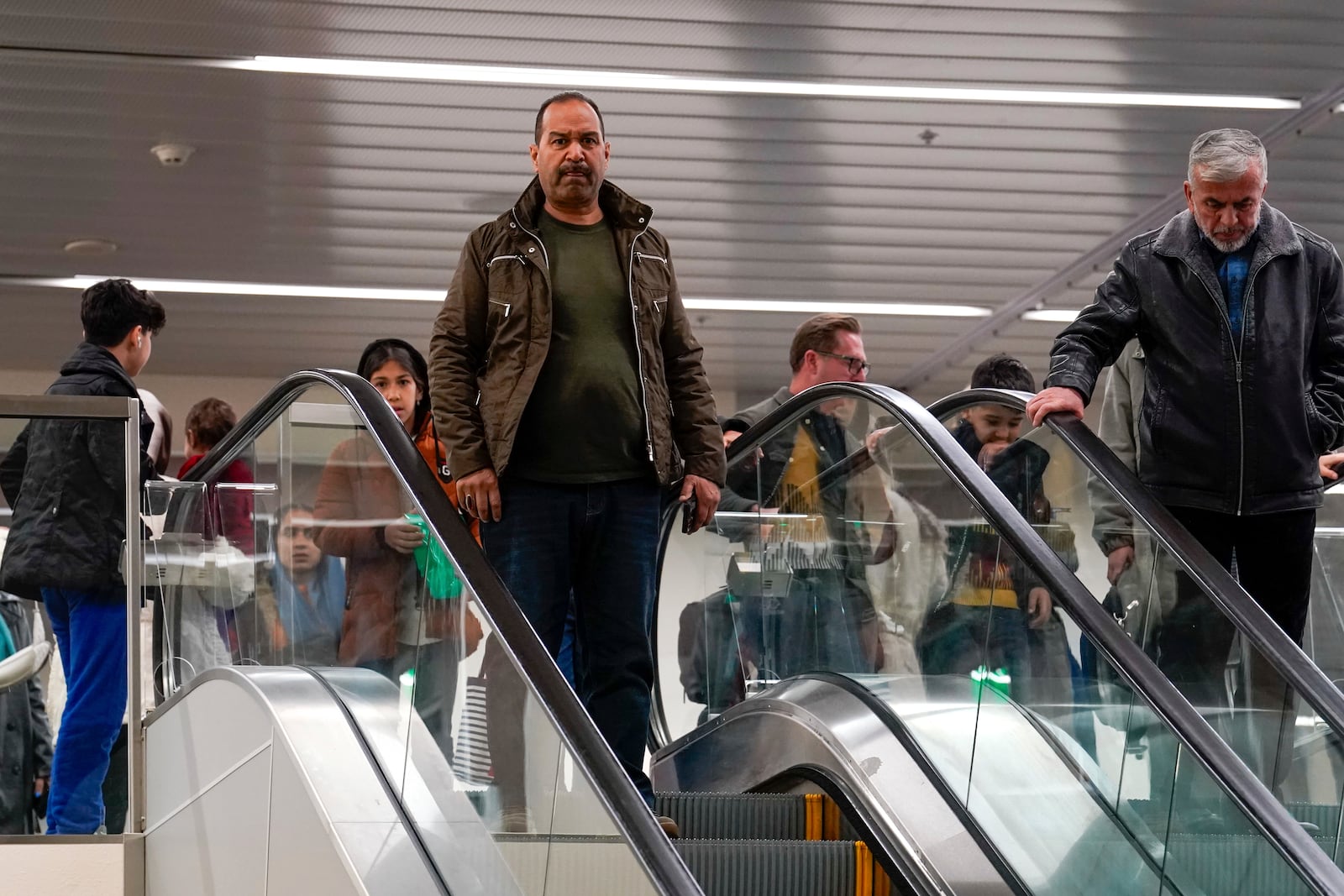 After leaving Afghanistan two-months earlier, Mohammed Saboor Osmani, center, followed by his family, takes the escalator down to the baggage area of the Sacramento International Airport in Sacramento, Calif., Tuesday, March 11, 2025. (AP Photo/Rich Pedroncelli)