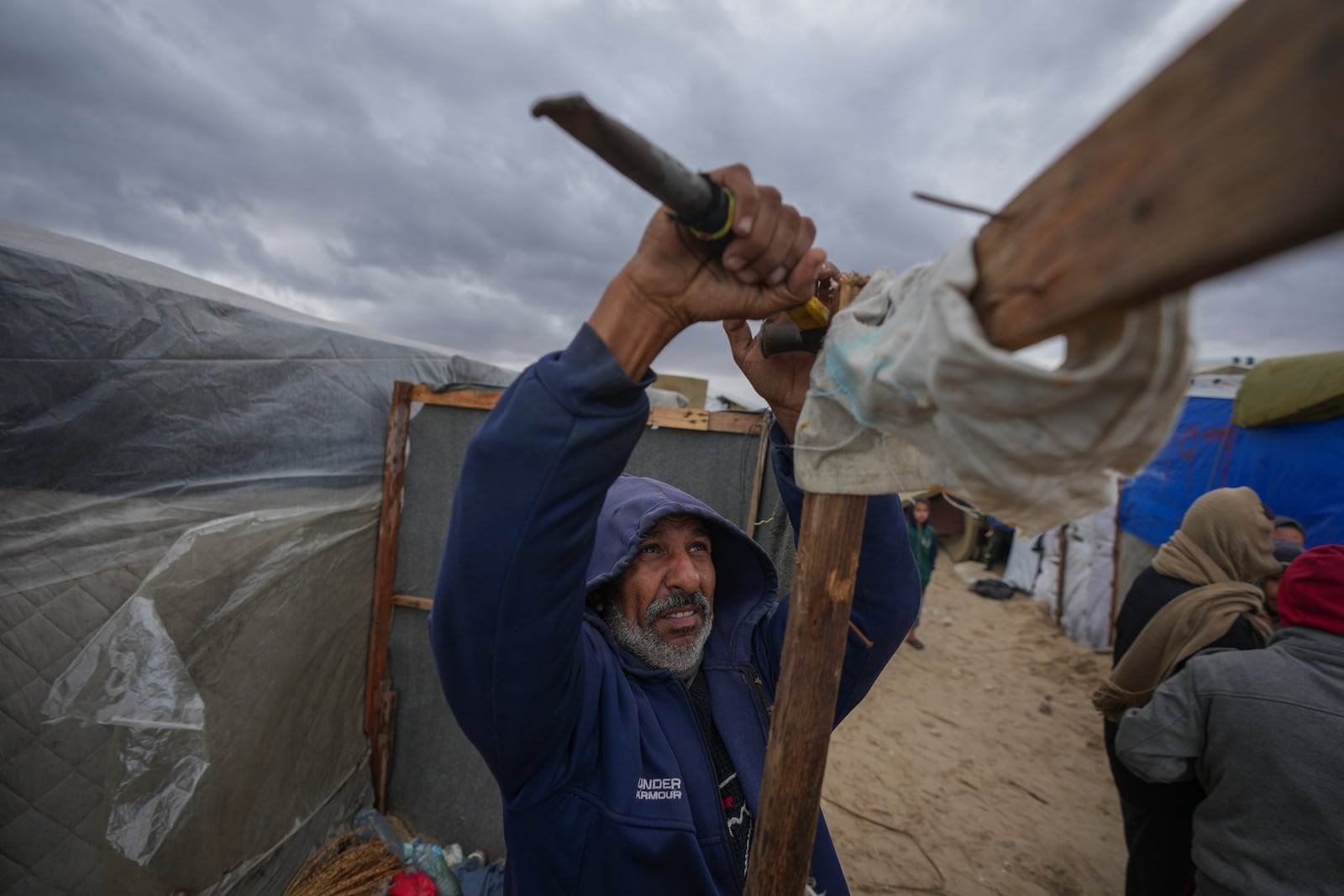 A Palestinian secures his tent as storm clouds loom over a camp for displaced Palestinians on the beach front in Deir al-Balah, Gaza Strip, Tuesday Nov. 26, 2024. (AP Photo/Abdel Kareem Hana)