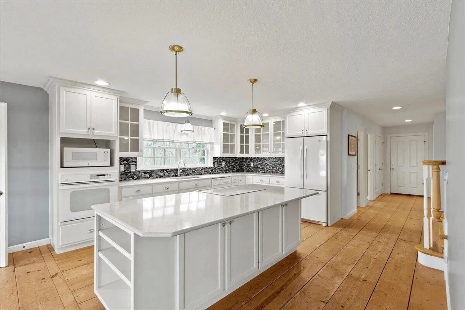 The kitchen includes an island with pendant lighting, white cabinets and quartz counters.