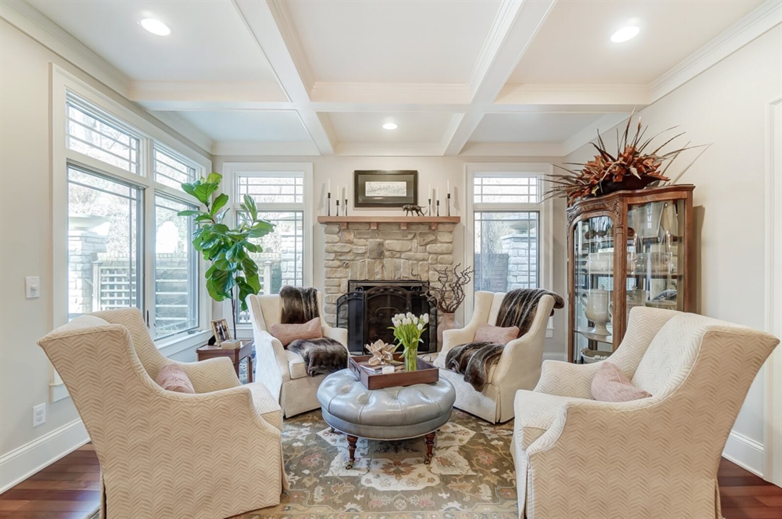 In the hearth room, a stone gas fireplace with wood-plank mantel is flanked by windows.