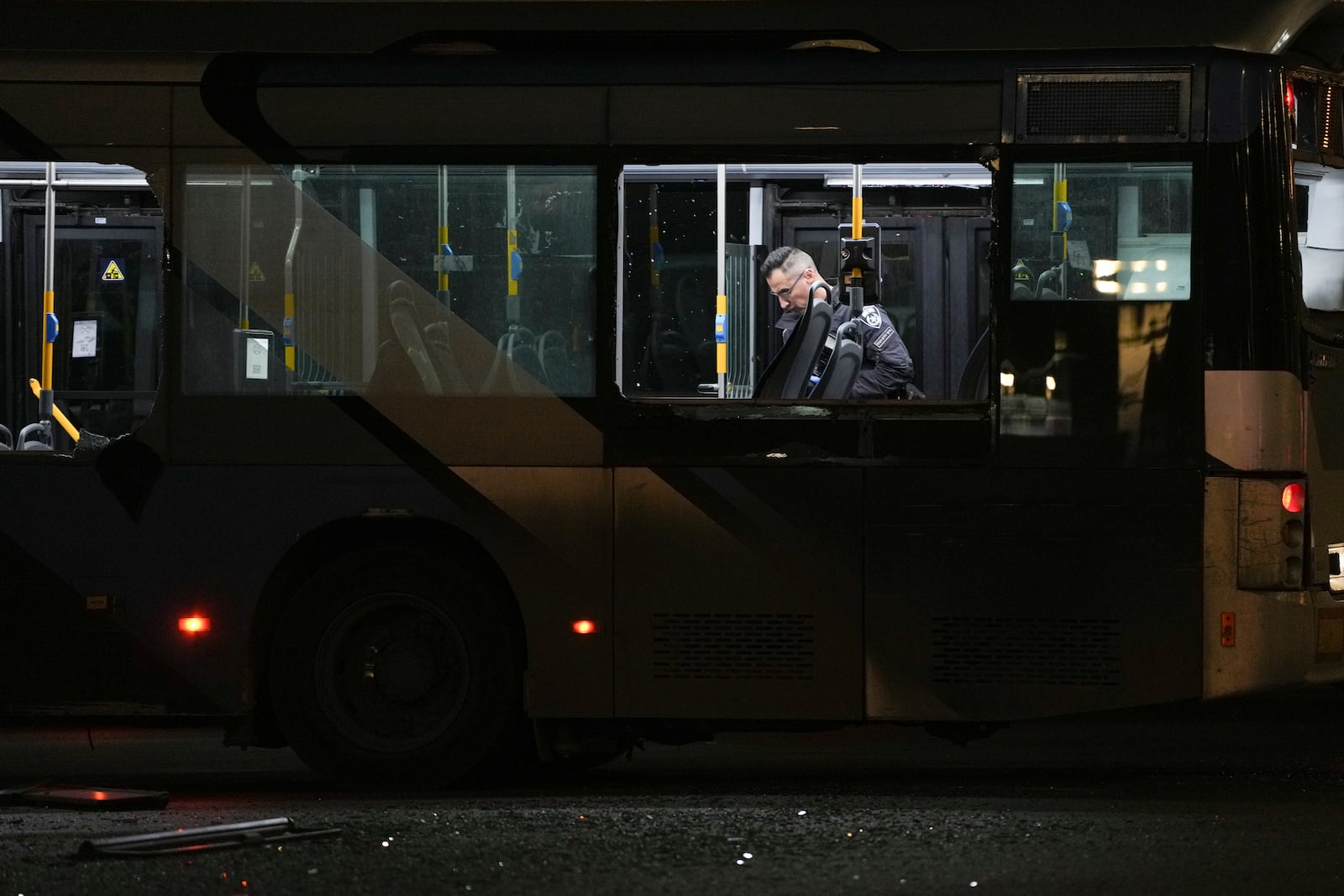 An Israeli police officer inspect the scene where police have reported a series of explosions on buses in what they said appeared to be a militant attack in Bat Yam, central Israel, Thursday Feb. 20, 2025. No injuries were reported. (AP Photo/Ohad Zwigenberg)