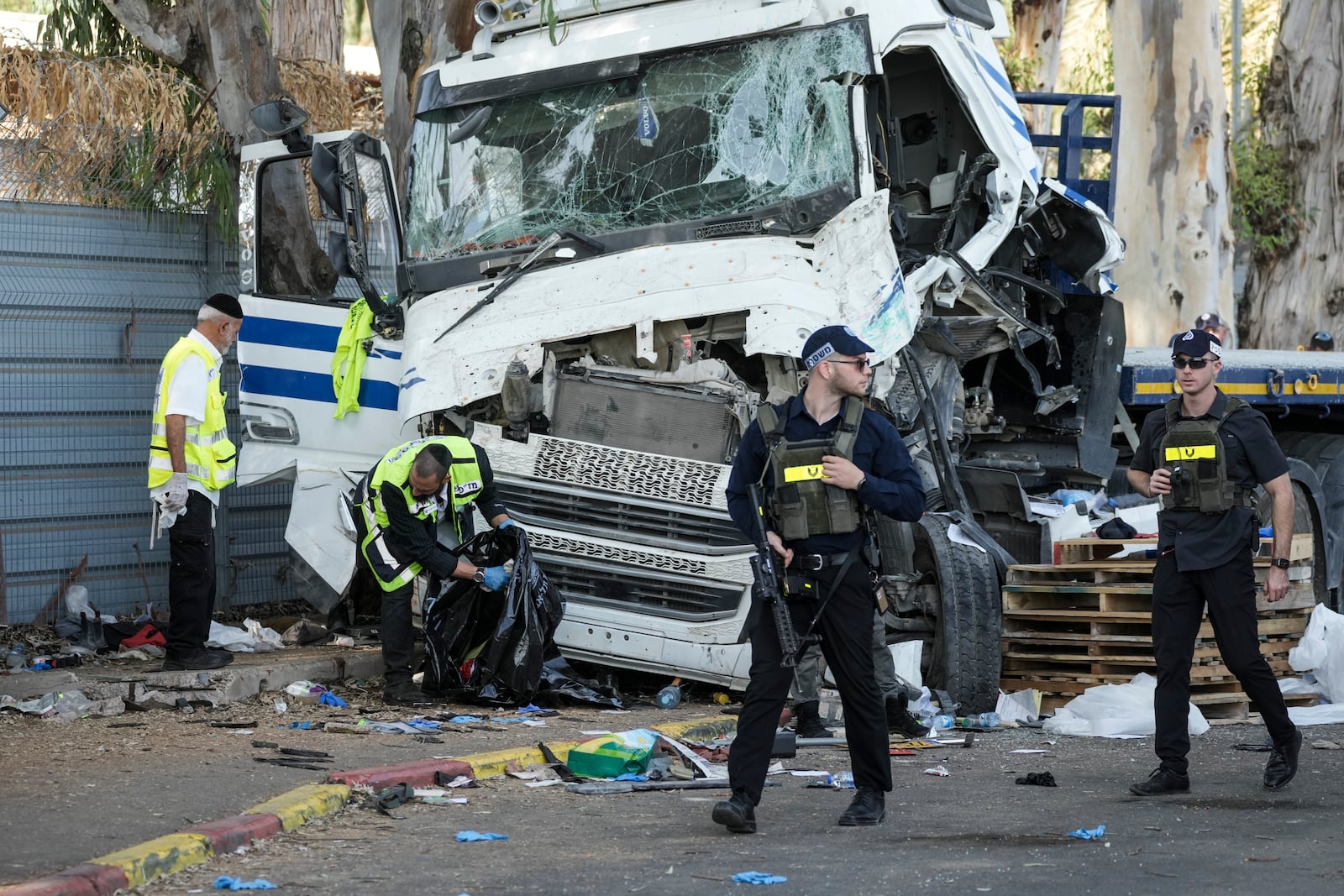 Israeli police and rescue services inspect the site where a truck driver rammed into a bus stop near the headquarters of Israel's Mossad spy agency, wounding dozens of people, according to Israel's Magen David Adom rescue service in Tel Aviv, Israel, Sunday, Oct. 27, 2024. (AP Photo/Oded Balilty)