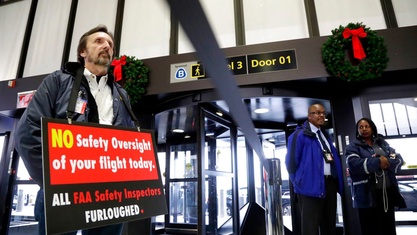 Federal Aviation Administration employee Michael Jessie, who is currently working without pay as an aviation safety inspector for New York international field office overseeing foreign air carriers, holds a sign while attending a news conference at Newark Liberty International Airport, Tuesday, Jan. 8, 2019, in Newark, N.J. U.S. Sens. Cory Booker and Bob Menendez called a news conference at the airport to address the partial government shutdown, which is keeping some airport employees working without pay.