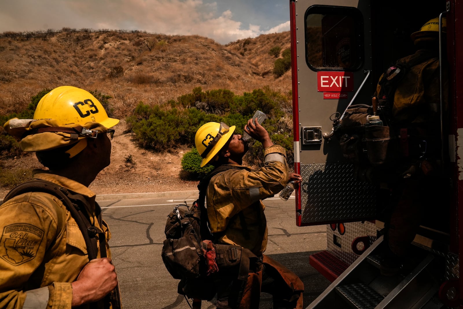 FILE - Firefighter Geo Mulongo, center, finishes his water while taking a break during the Line Fire in Highland, Calif., Sept. 6, 2024. (AP Photo/Jae C. Hong, File)