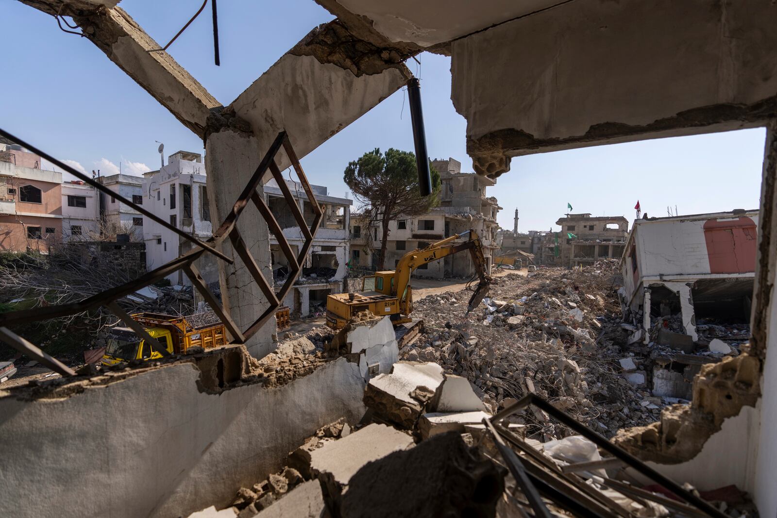 A bulldozer equipped with a drill works on the rubble of destroyed houses, caused by the Israeli air and ground offensive, in the town of Khiam, southern Lebanon, Monday, Feb. 17, 2025. (AP Photo/Hassan Ammar)