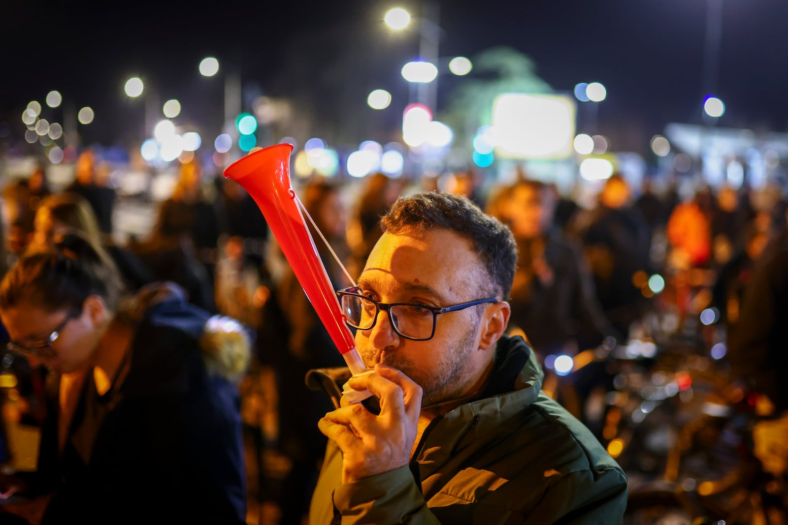 A man blows a horn during a protest over the collapse of a concrete canopy that killed 15 people more than two months ago, in Novi Sad, Serbia, Friday, Jan. 31, 2025. (AP Photo/Armin Durgut)