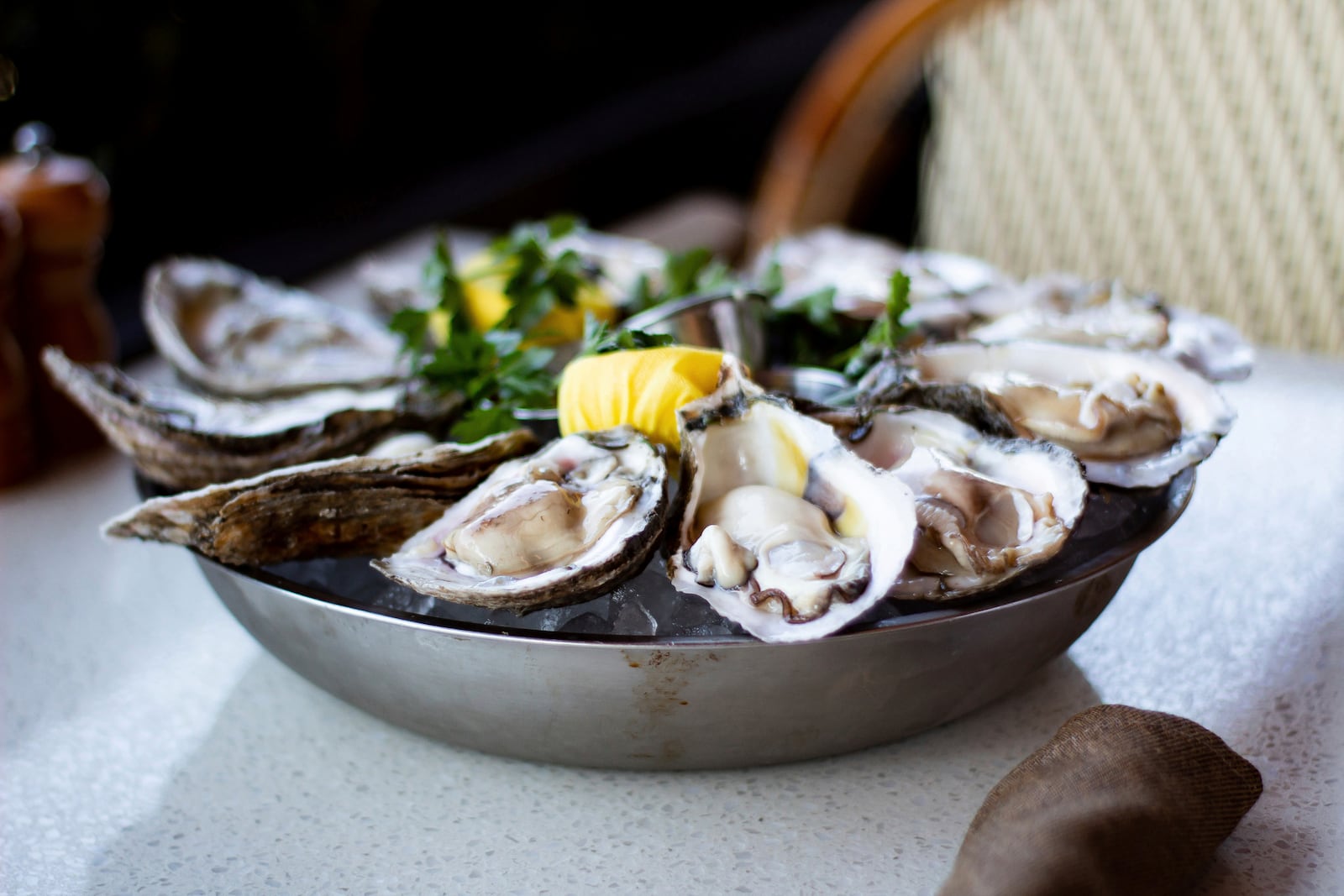 A plate of fresh, raw oysters with lemon and parsley sits on a table at C&S Seafood and Oyster Bar in Sandy Springs, Ga., on Feb. 11, 2022. Georgia’s oyster industry is hampered by a lack of commercial oyster hatcheries and a limited harvest season. The state legalized commercial oyster farming three years ago. There are now 19 privately held leases growing oysters off the coast.(Sarah Swetlik/Fresh Take Georgia via AP)