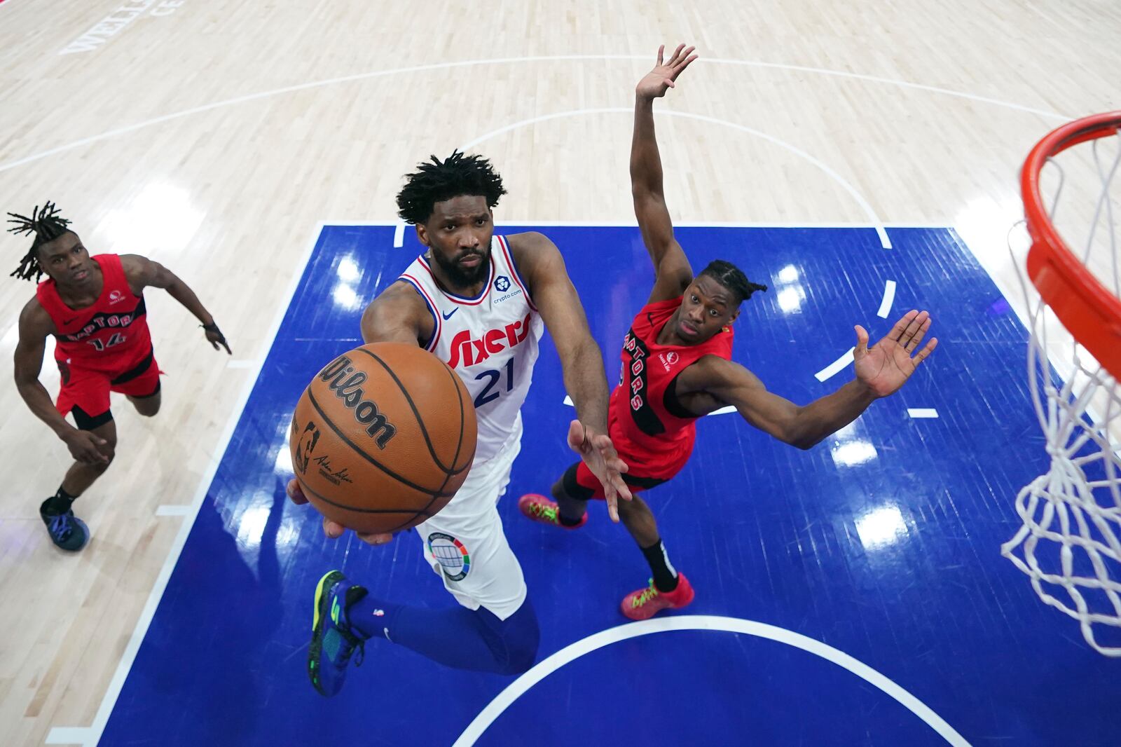 Philadelphia 76ers' Joel Embiid, center, goes up for a shot against Toronto Raptors' Jonathan Mogbo during the second half of an NBA basketball game, Tuesday, Feb. 11, 2025, in Philadelphia. (AP Photo/Matt Slocum)