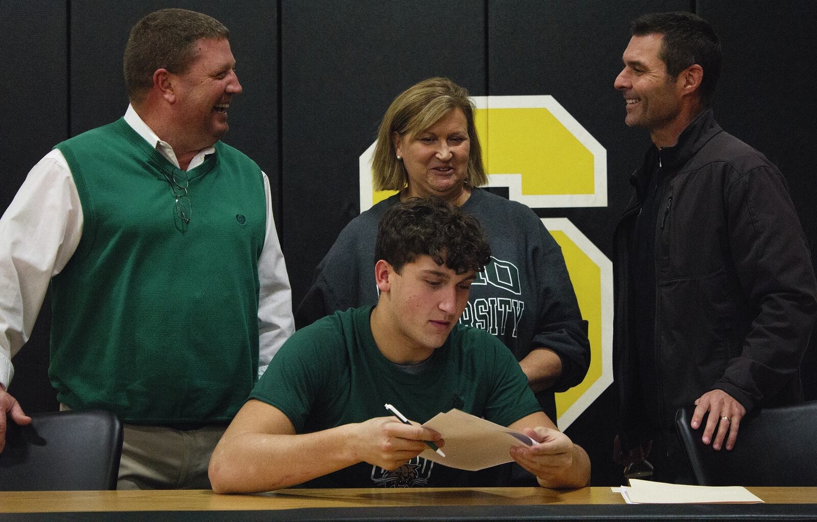 Shawnee linebacker Jack McCrory signs with Ohio University on Wednesday in the company of Braves coach Rick Meeks (left) and his parents Tony and Phyllis McCrory. JEFF GILBERT / CONTRIBUTED