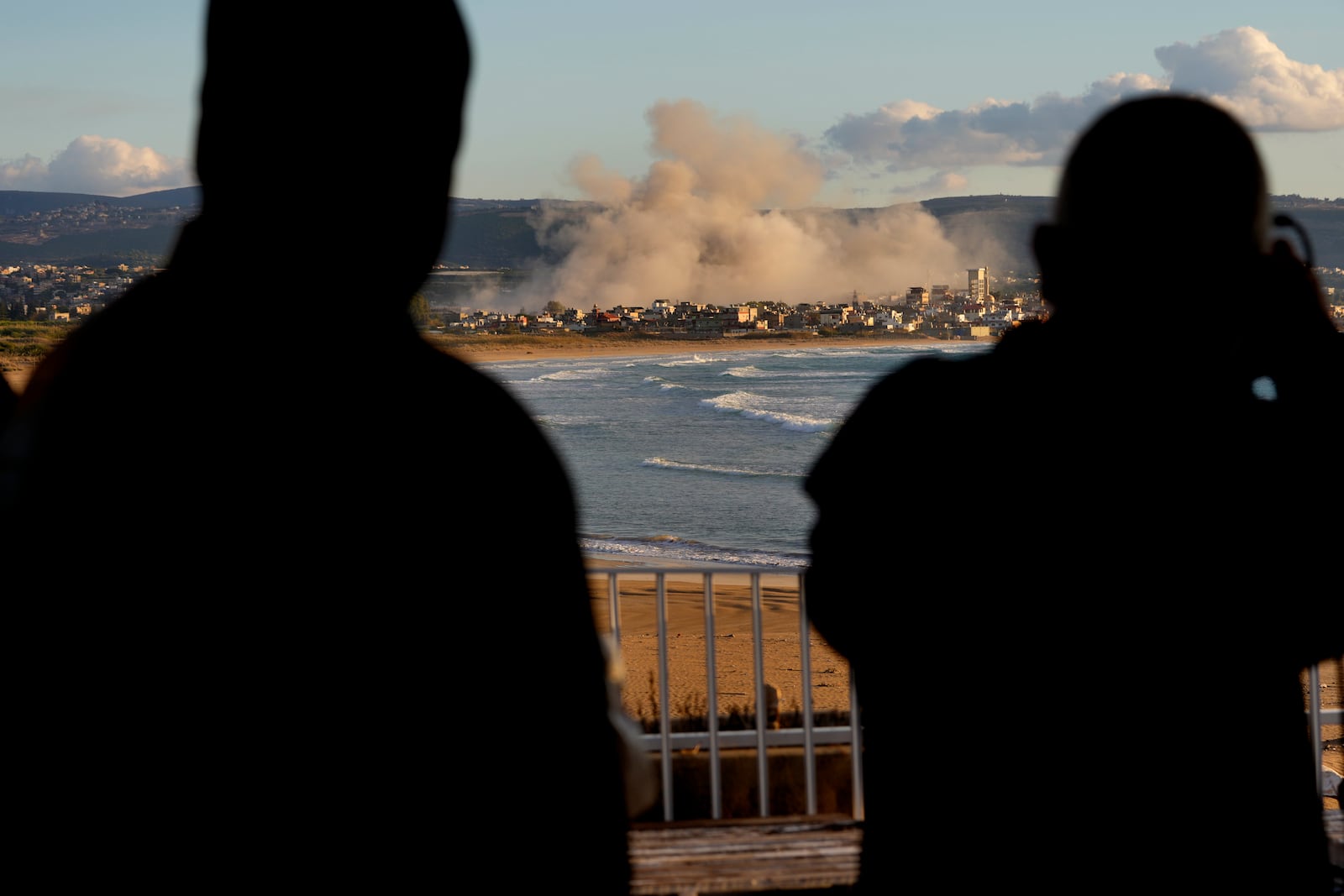 Journalists watch the smoke rising between buildings hit in Israeli airstrikes near the Palestinian refugee camp of Rashidiyeh, as it seen from Tyre city, south Lebanon, Tuesday, Nov. 26, 2024. (AP Photo/Hussein Malla)