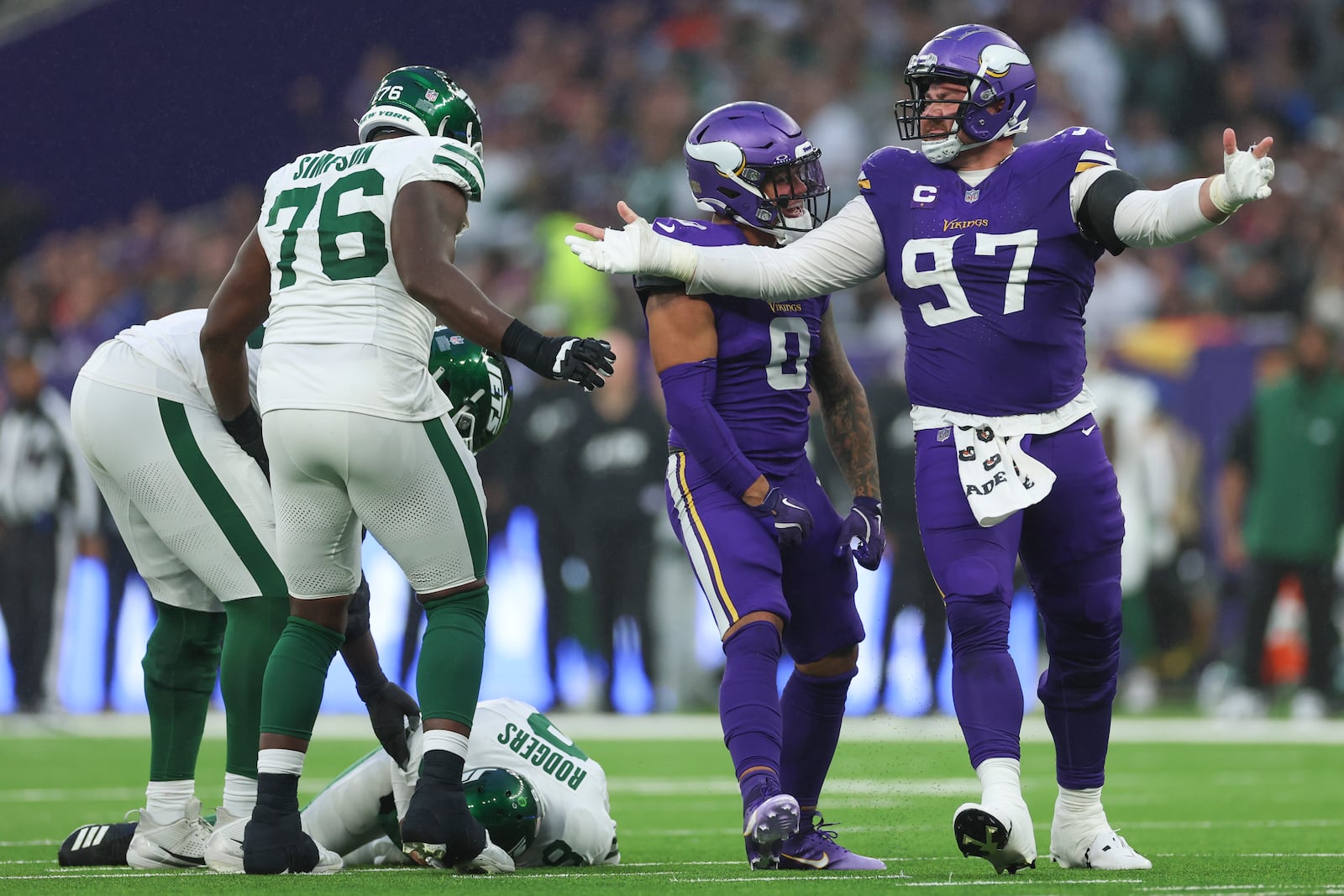 Minnesota Vikings' Harrison Phillips (97), right, celebrates his sack of New York Jets quarterback Aaron Rodgers, bottom left, during the second half of an NFL football game, Sunday, Oct. 6, 2024, at the Tottenham Hotspur stadium in London. (AP Photo/Ian Walton)