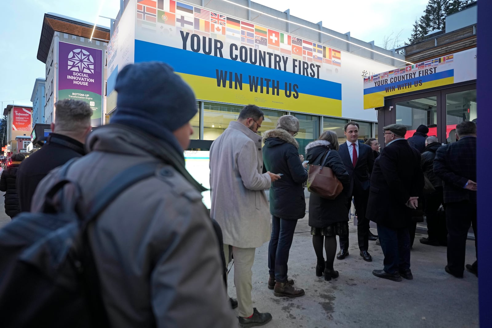 People line up in front of the Ukraine house to watch the inauguration of Donald Trump on screens alongside the World Economic Forum in Davos,Switzerland, Monday, Jan. 20, 2025. (AP Photo/Markus Schreiber)