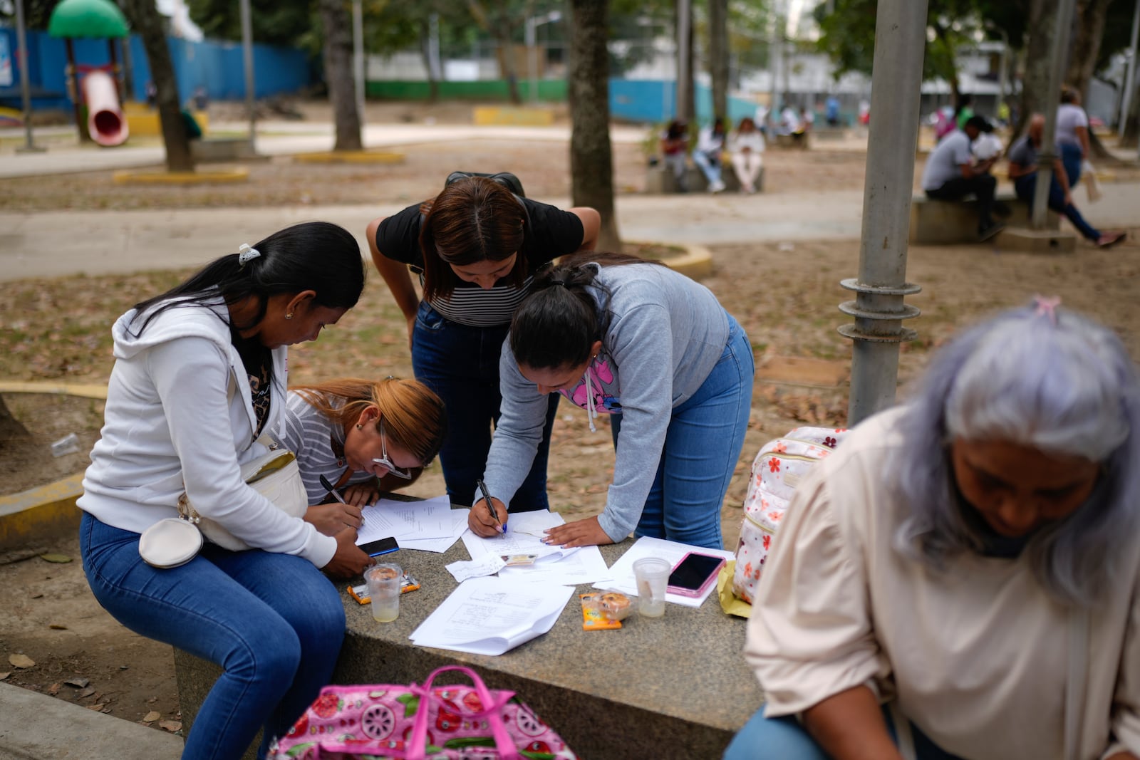 Relatives of prisoners detained in a post-election crackdown fill out forms to give to Attorney General Tarek William Saab, outside his office in Caracas, Venezuela, Thursday, Jan. 16, 2025. (AP Photo/Ariana Cubillos)