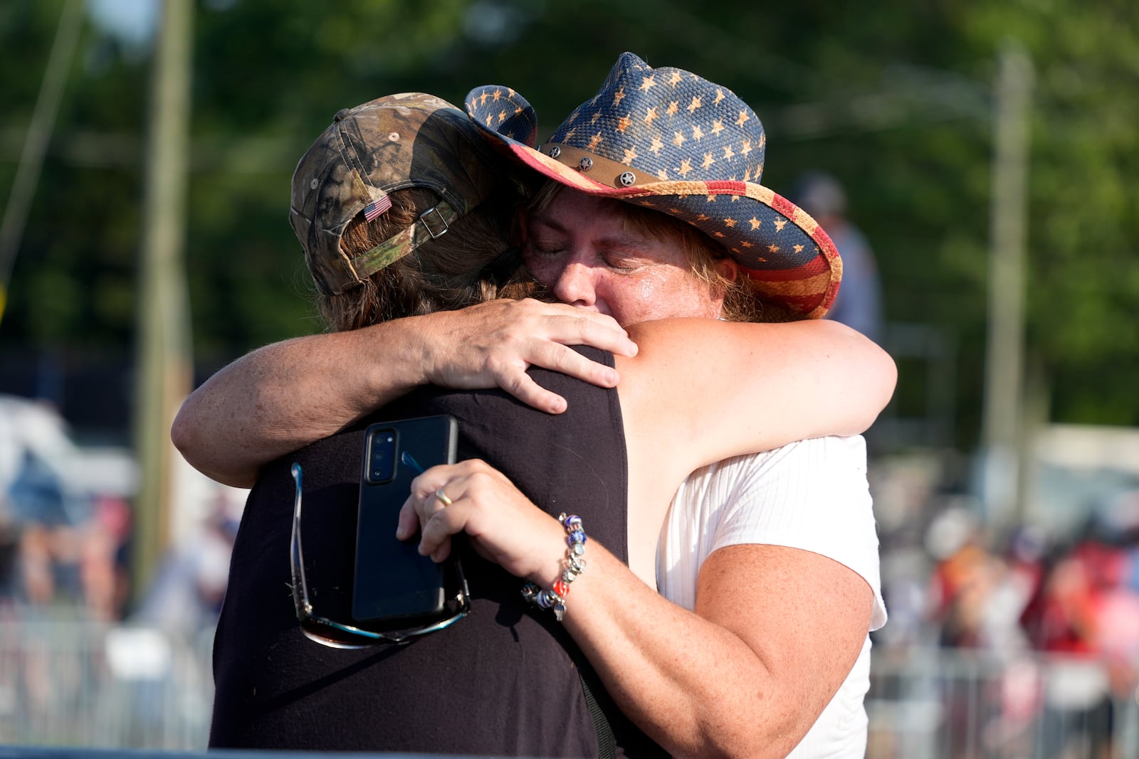 FILE - People hug after Republican presidential candidate former President Donald Trump was helped off the stage at a campaign event in Butler, Pa., July 13, 2024. (AP Photo/Gene J. Puskar, File)