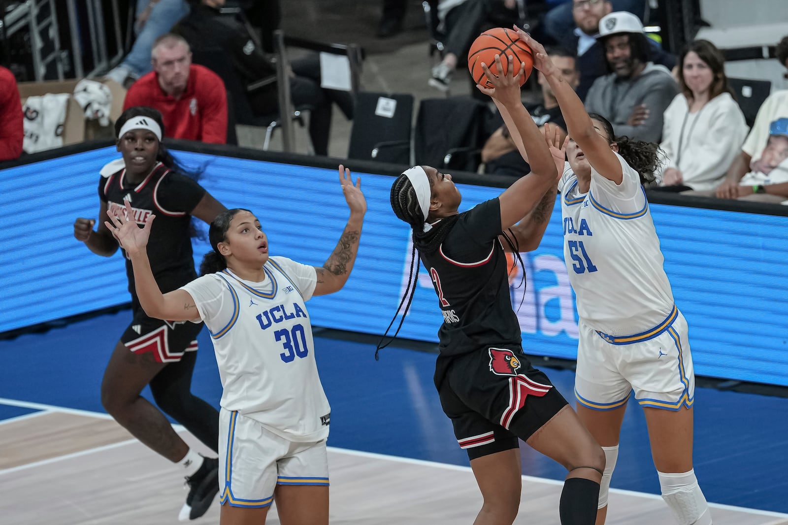 UCLA center Lauren Betts, right, blocks a shot by Louisville forward Nyla Harris, second from right, during an NCAA college basketball game Monday, Nov. 4, 2024, in Paris, France. (AP Photo/Aurelien Morissard)