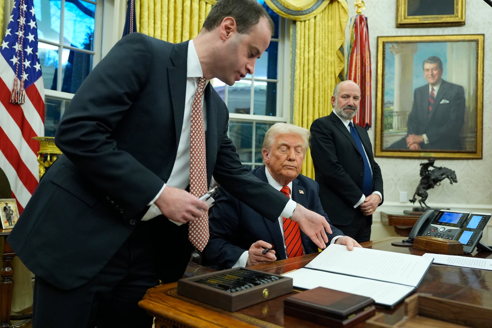 White House staff secretary Will Scharf hands President Donald Trump an executive order to sign in the Oval Office at the White House, Monday, Feb. 10, 2025, in Washington, as Commerce Secretary nominee Howard Lutnick watches. (Photo/Alex Brandon)