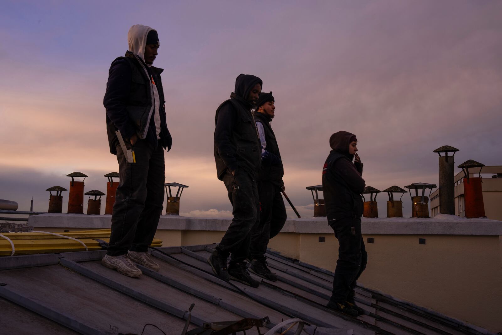 Roofers leave the roof of a building after a work day in Paris, Wednesday, Nov. 20, 2024. (AP Photo/Louise Delmotte)