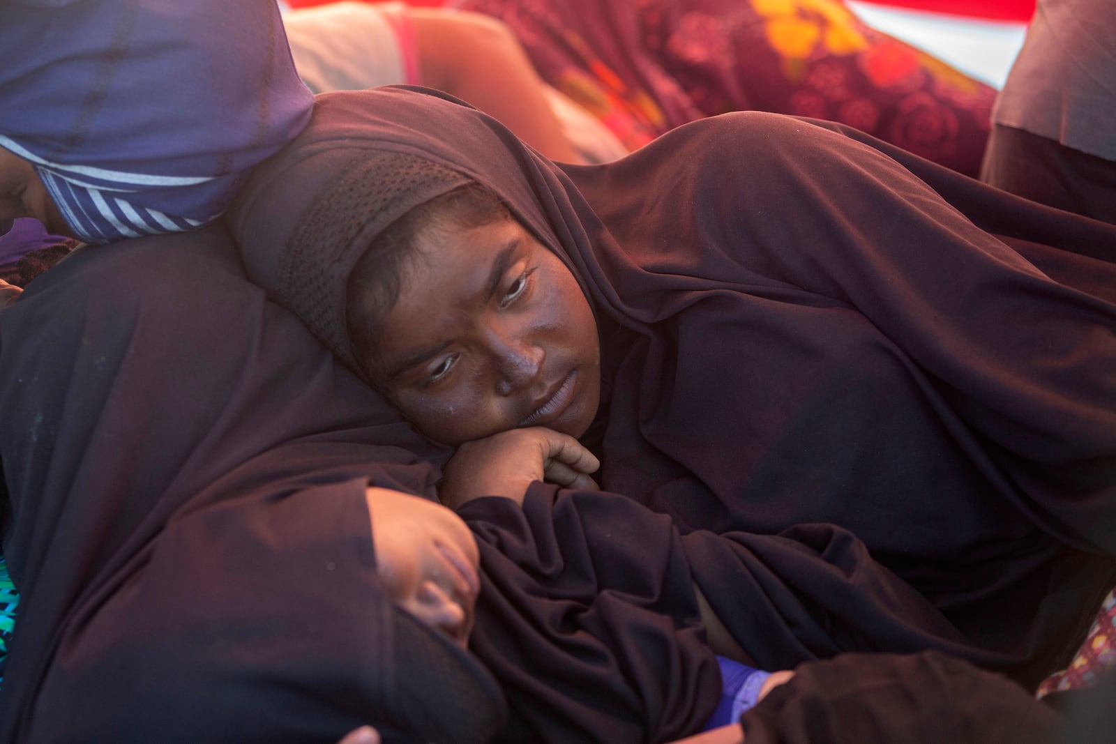 A Rohingya woman rests on the deck of a boat carrying refugees anchored in the waters near the coast of Labuhan Haji, Aceh province, Indonesia, Tuesday, Oct. 22, 2024. (AP Photo/Binsar Bakkara)