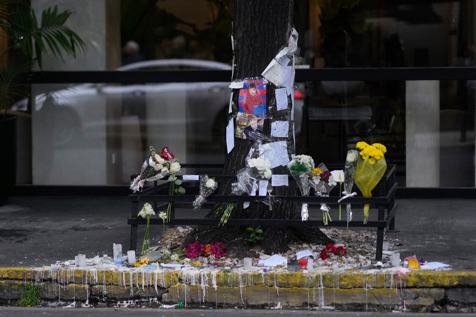 Photos of former One Direction singer Liam Payne, along with flowers and messages from fans, are attached to a tree outside the hotel where he was found dead after falling from a balcony in Buenos Aires, Argentina, the morning after the incident, Thursday, Oct. 17, 2024. (AP Photo/Natacha Pisarenko)