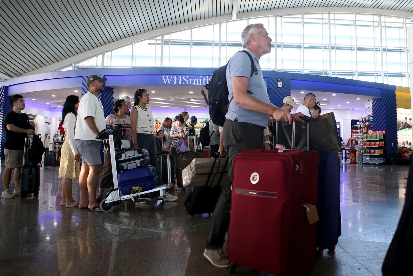 Passengers look at a flight information board after a number of flights are cancelled due to the eruption of Mount Lewotobi Laki-Laki, at Ngurah Rai International Airport in Bali, Indonesia, Wednesday, Nov. 13, 2024. (AP Photo/Firdia Lisnawati)