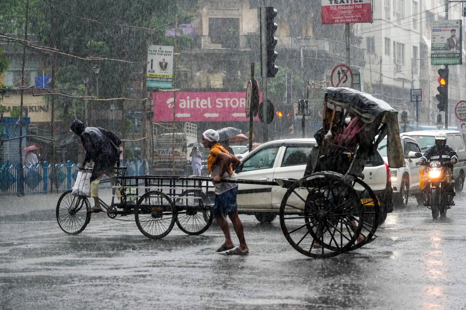 A hand-rickshaw puller carries passengers during heavy rain following tropical storm Dana, in Kolkata, India, Friday, Oct. 25, 2024. (AP Photo/Bikas Das)