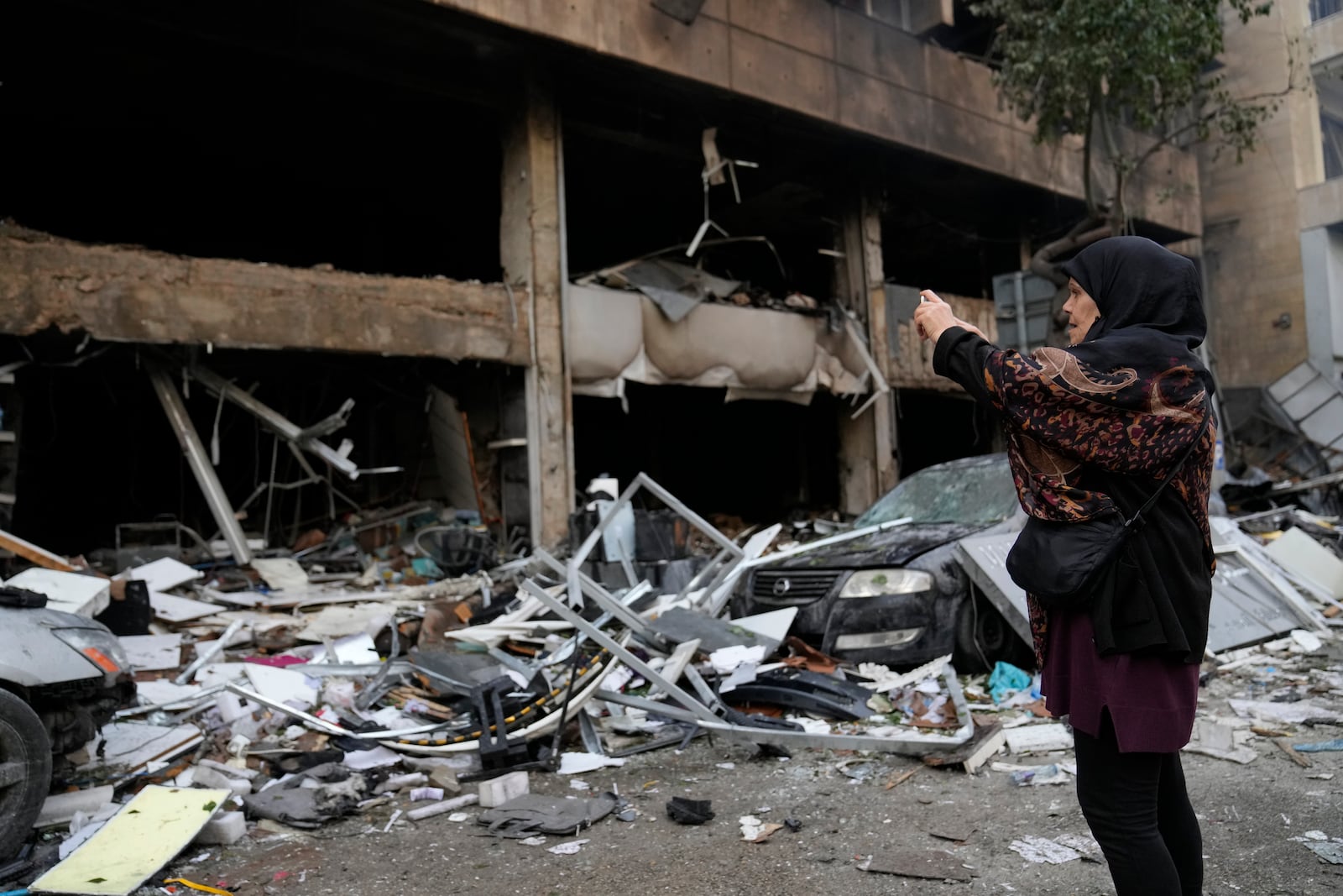 A woman uses her phone to record destroyed shops that were hit Sunday evening by an Israeli airstrike in central Beirut, Lebanon, Monday, Nov. 18, 2024. (AP Photo/Hussein Malla)