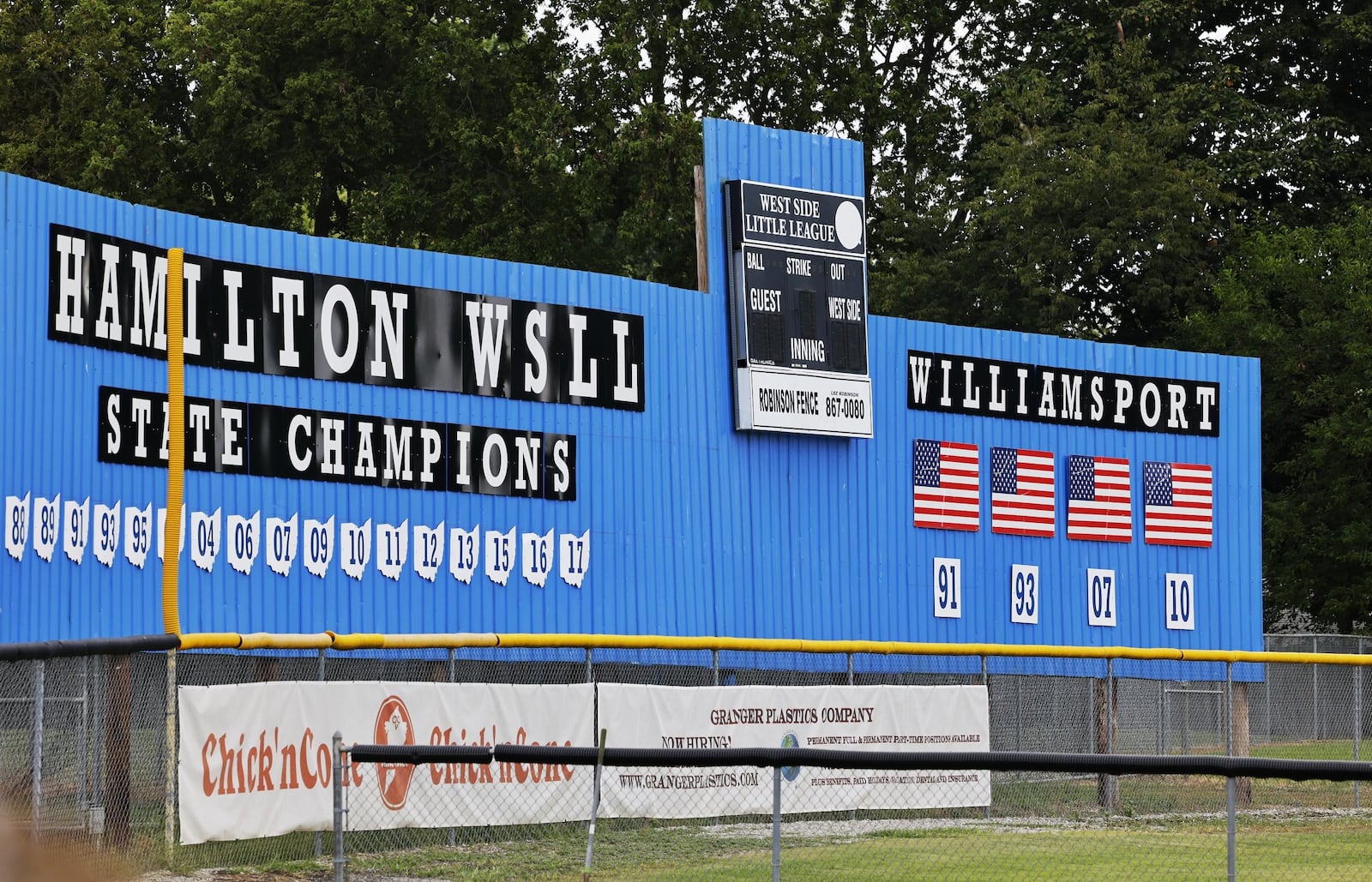 The leftfield wall at the Hamilton West Side baseball diamond honors those teams that won the Little League state title and those that qualified for the World Series. The wall will need updated after the team won the 2019 and 2021 state championships and advanced to this year's World Series. NICK GRAHAM/STAFF