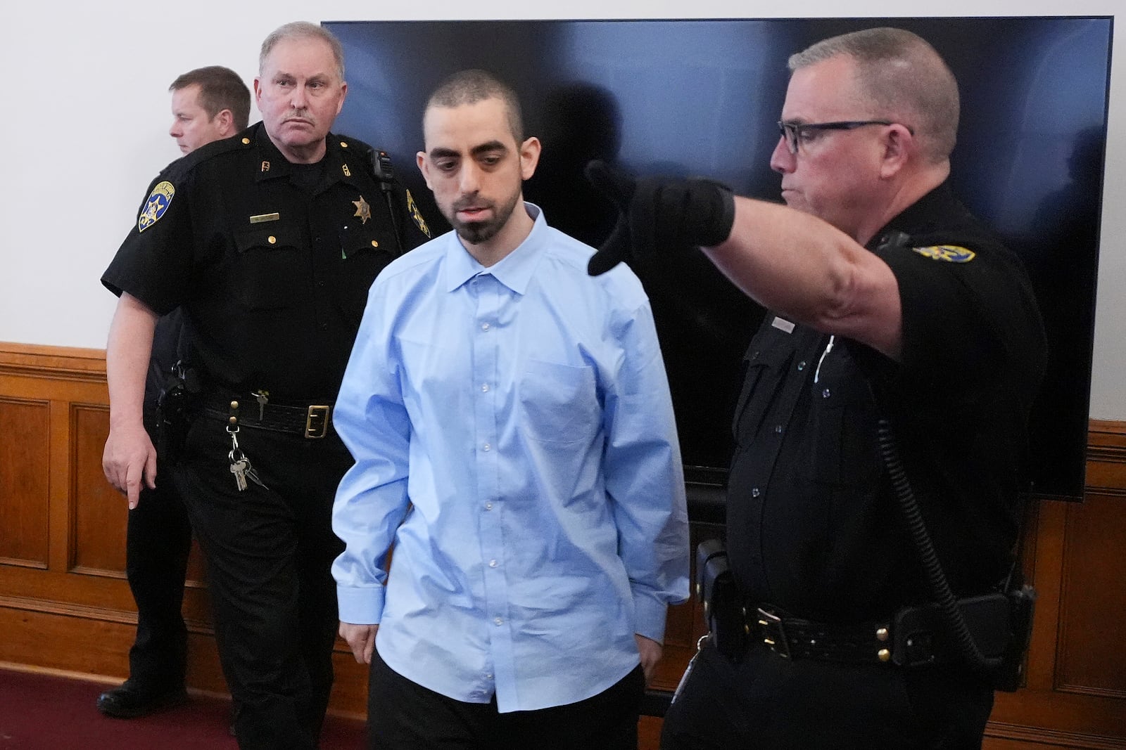 Hadi Matar, center, is escorted into the courtroom at the Chautauqua County Courthouse ahead of the second day in his trial, Tuesday, Feb. 11, 2025, in Mayville, N.Y. Matar is charged with stabbing famed author Salman Rushdie. (AP Photo/Gene J. Puskar)