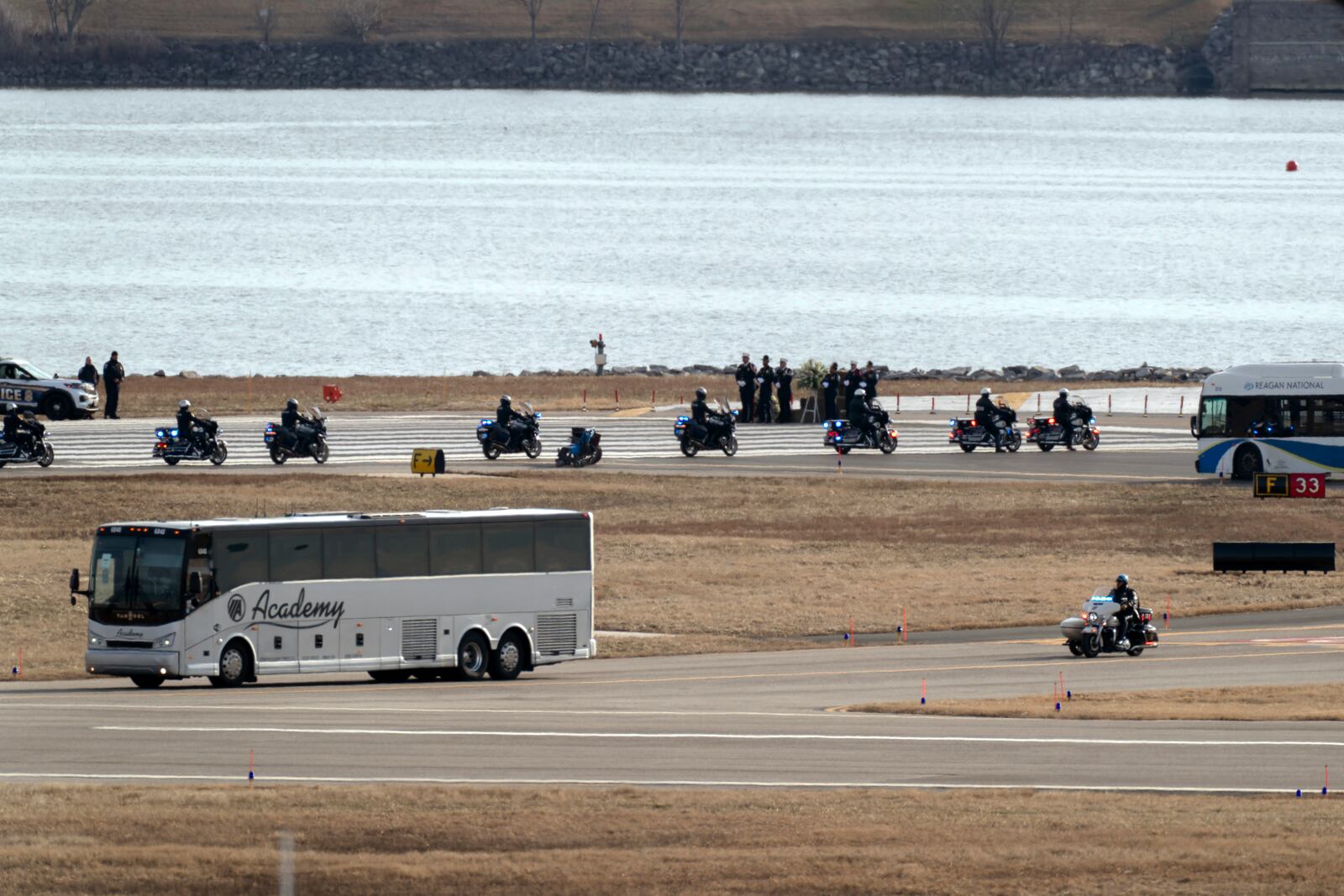 Buses carrying family members of the victims of a mid-air collision between an American Airlines jet and an Army helicopter arrive to runway 33 near the wreckage site in the Potomac River at Ronald Reagan Washington National Airport, Sunday, Feb. 2, 2025, in Arlington, Va. (AP Photo/Jose Luis Magana)