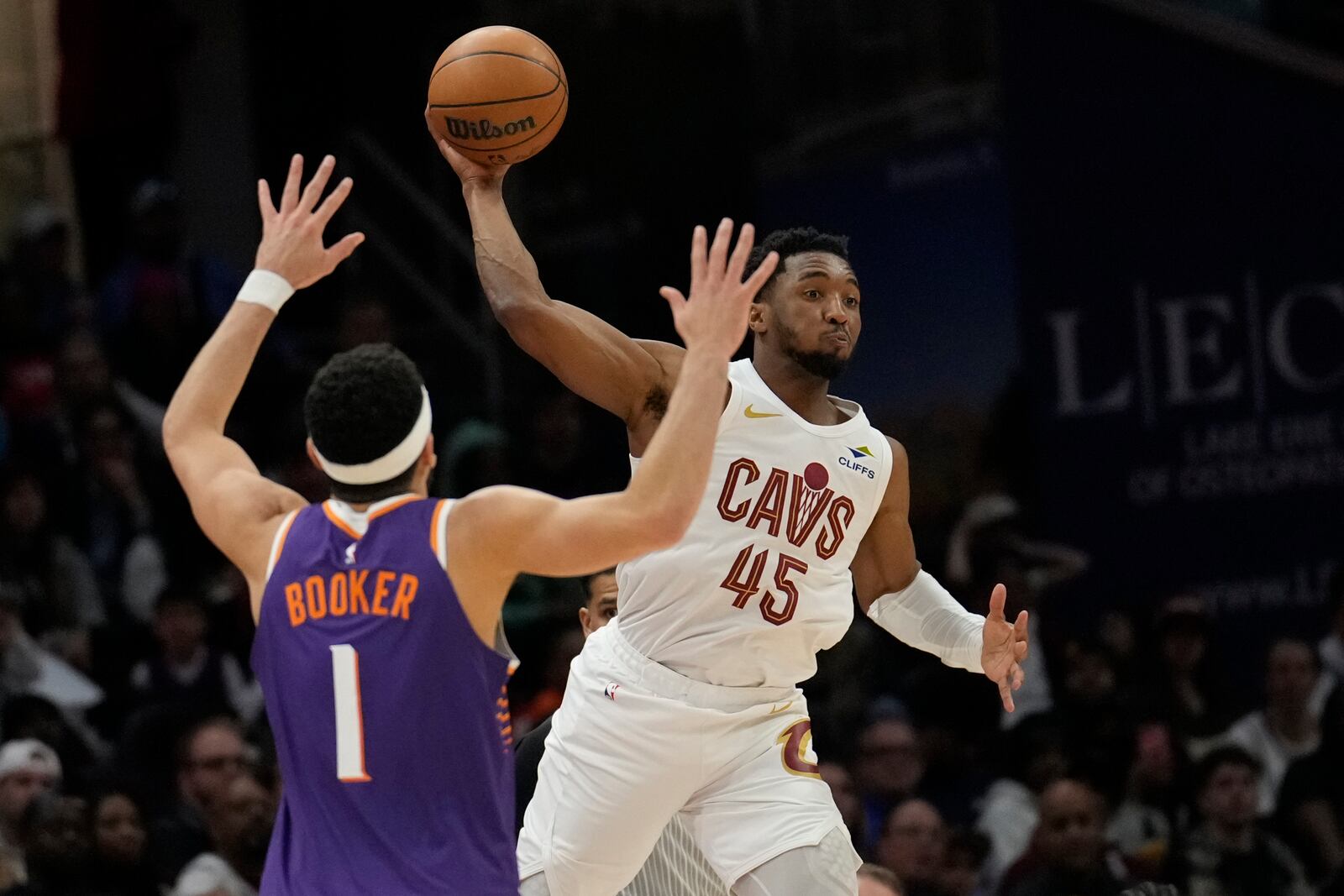 Cleveland Cavaliers guard Donovan Mitchell (45)looks to pass the ball as Phoenix Suns guard Devin Booker (1) defends in the second half of an NBA basketball game, Monday, Jan. 20, 2025, in Cleveland. (AP Photo/Sue Ogrocki)