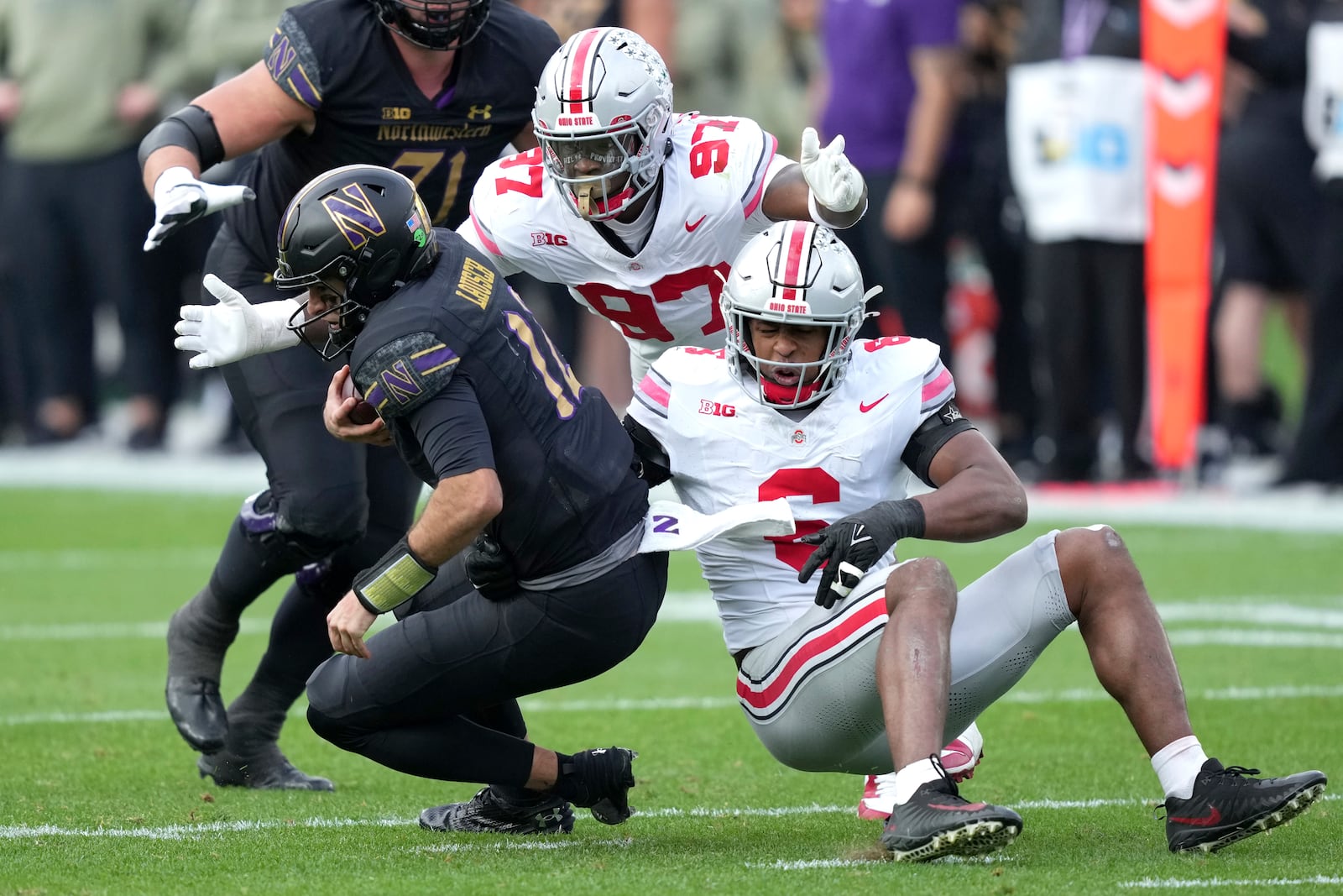 Ohio State safety Sonny Styles (6) and defensive end Kenyatta Jackson Jr. sack Northwestern quarterback Jack Lausch during the second half of an NCAA college football game at Wrigley Field on Saturday, Nov. 16, 2024, in Chicago. (AP Photo/Charles Rex Arbogast)