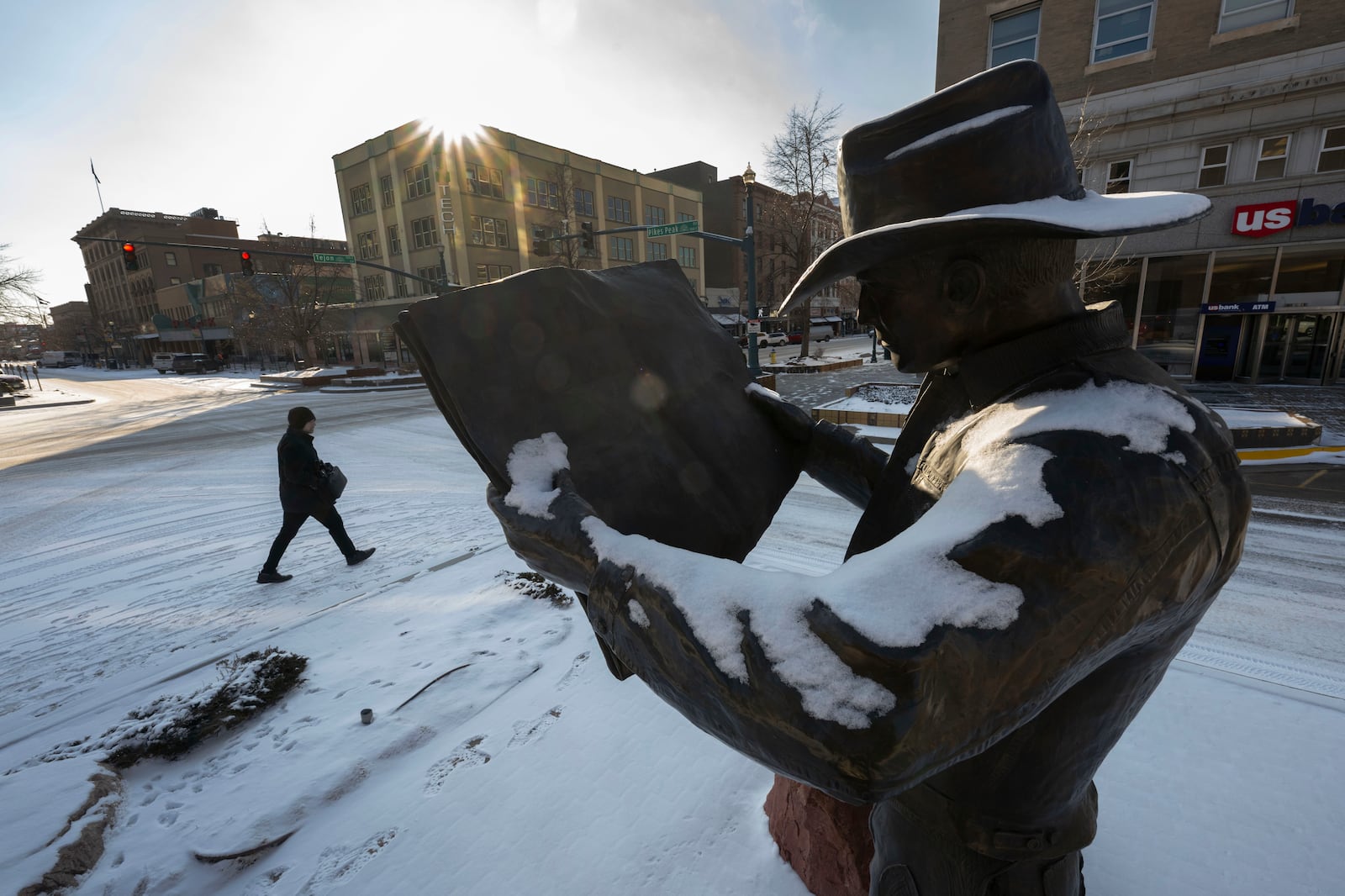 The sun begins to cast its light on the Hank the Cowboy statue in downtown Colorado Springs, Colo., as a pedestrian braves the single-digit temperatures Wednesday morning, Feb. 12, 2025. (Christian Murdock/The Gazette via AP)