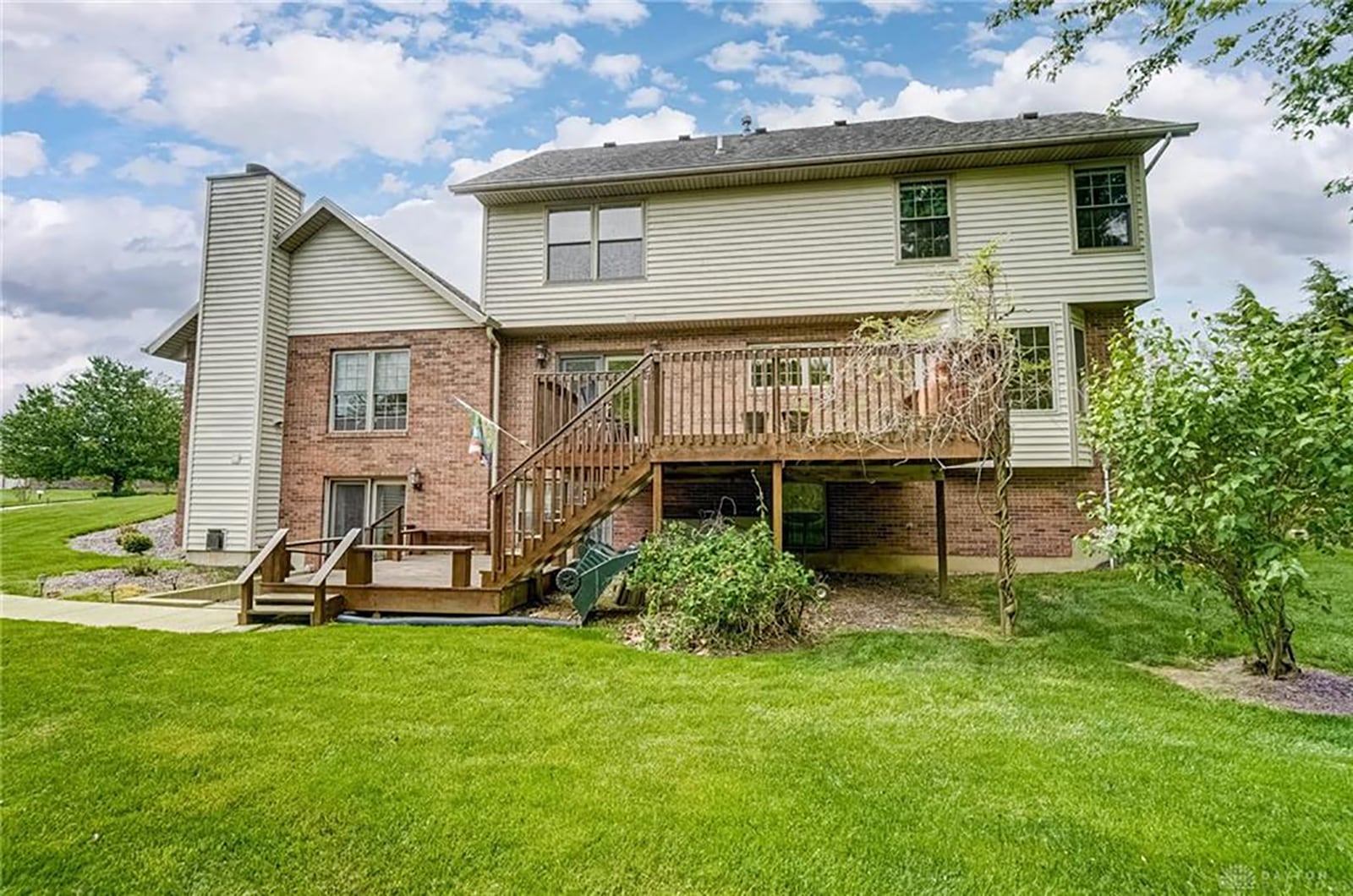 The rear of the home has a double-level wood deck with railings and a walkout from the basement to a concrete and gravel patio.