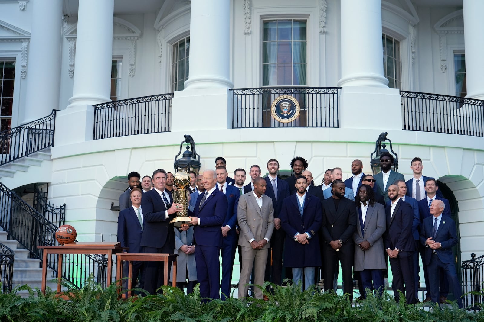 Boston Celtics owner Wyc Grousbeck, from left, and President Joe Biden hold up the Boston Celtics' trophy as they pose for a team photo to celebrate the Celtics victory in the 2024 National Basketball Association Championship during an event on the South Lawn of the White House in Washington, Thursday, Nov. 21, 2024. (AP Photo/Susan Walsh)