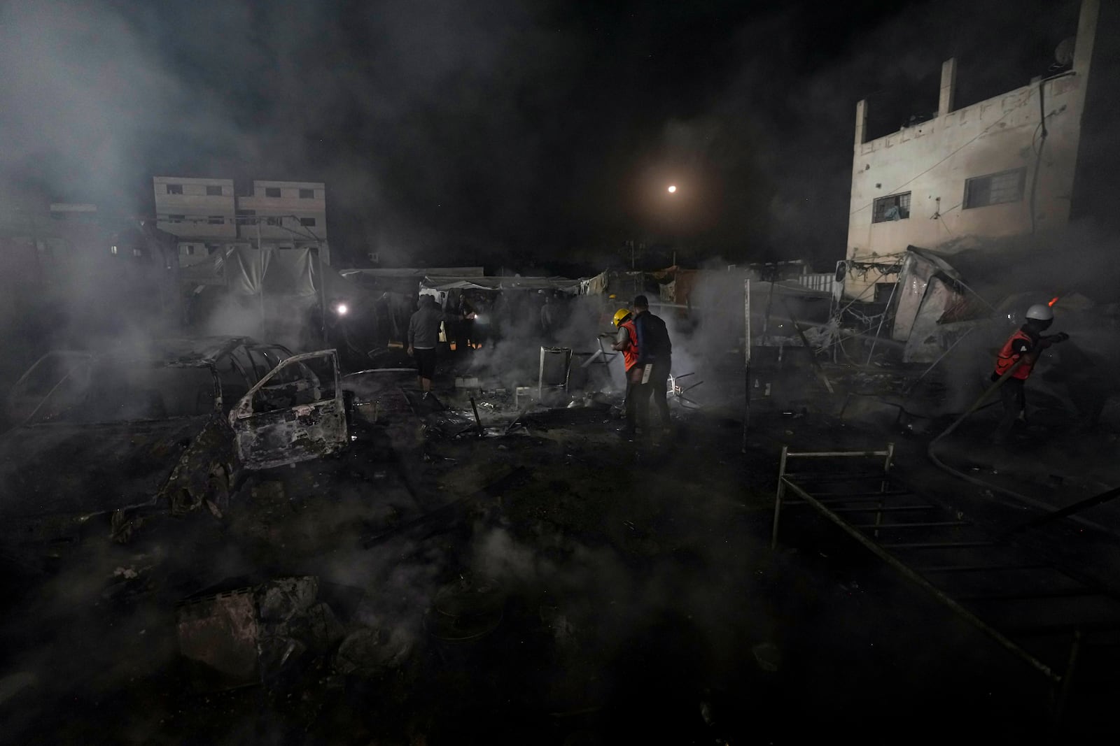 Palestinian firefighters try to extinguish a fire caused by an Israeli strike that hit a tent area in the courtyard of Al Aqsa Martyrs hospital in Deir al Balah, Gaza Strip, Monday, Oct. 14, 2024. (AP Photo/Abdel Kareem Hana)